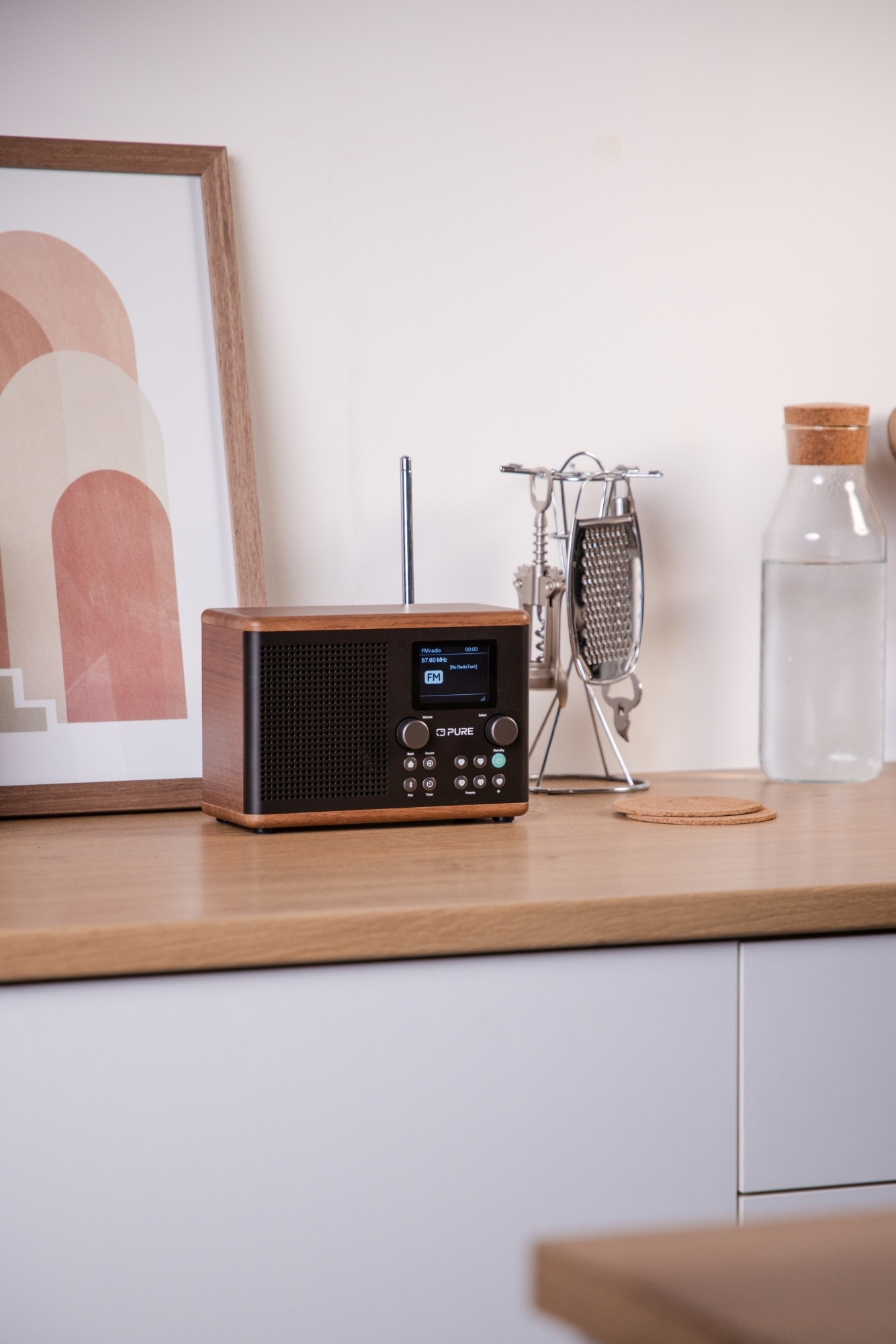 Radio en bois sur plan de travail, écran, boutons, et ustensiles métal.