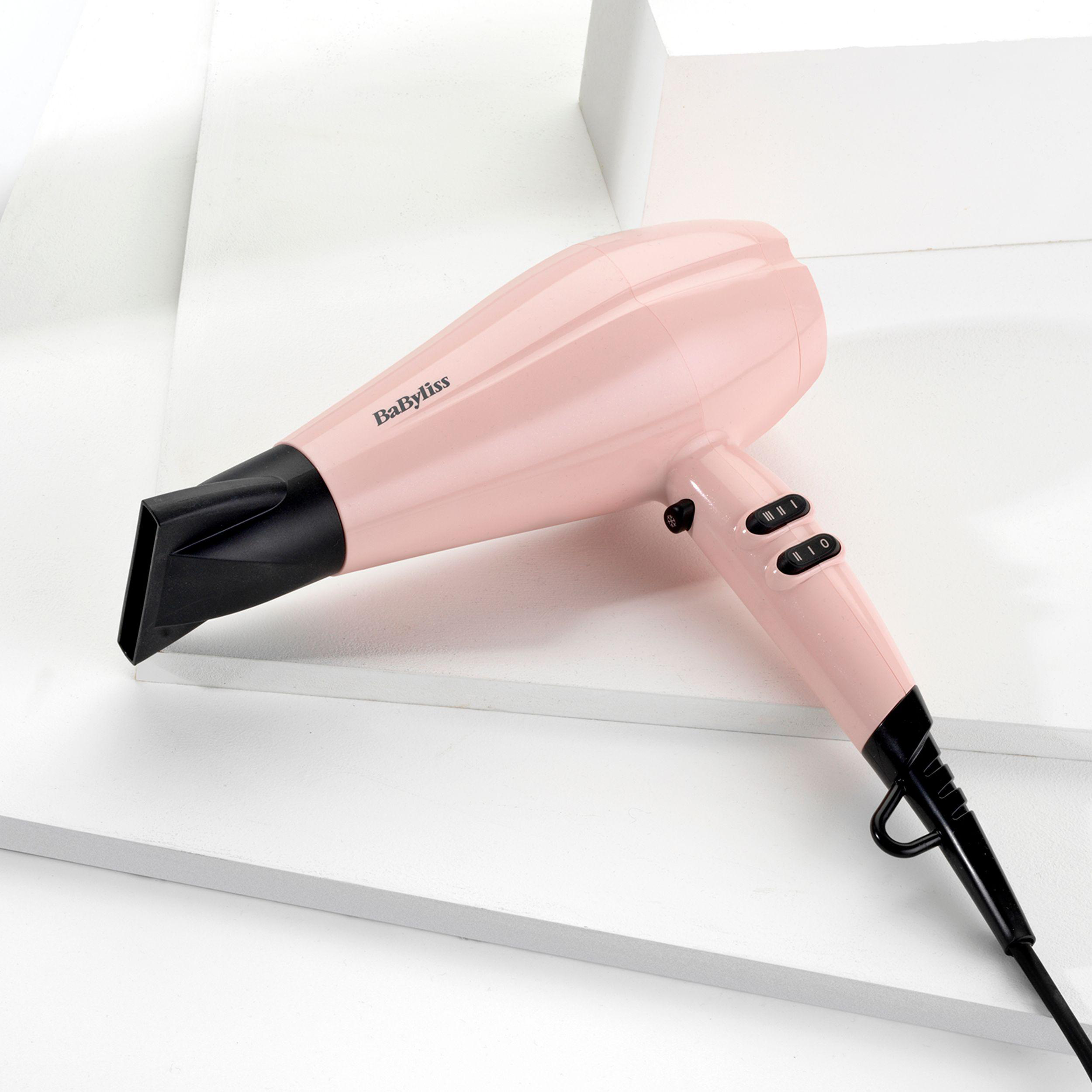 Pinker BaByliss-Haartrockner auf weißer Oberfläche mit schwarzer Düse und Bedienelementen.
