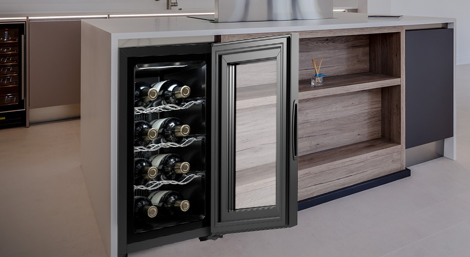 Se muestra una vinoteca integrada en una isla de cocina. Tiene una puerta de cristal con botellas de vino en su interior.