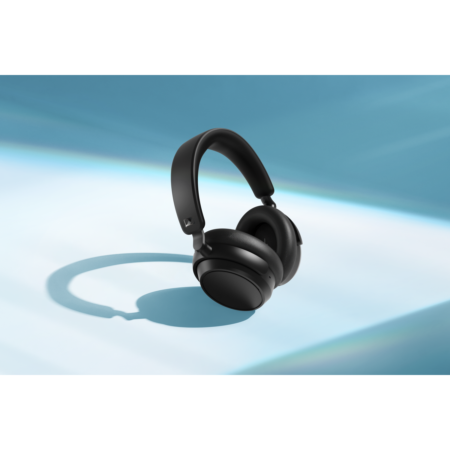Black headphones on a blue surface.  Headphones cast a shadow. 