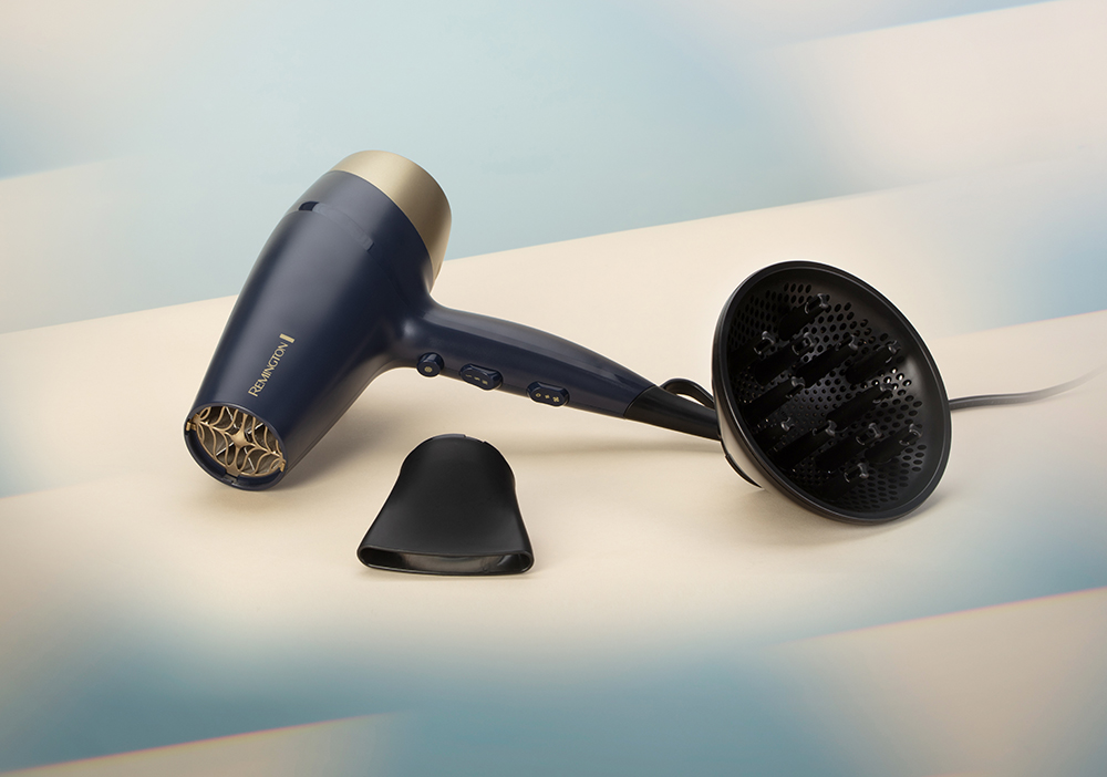 Secador de pelo Remington azul y dorado con accesorios sobre superficie blanca.