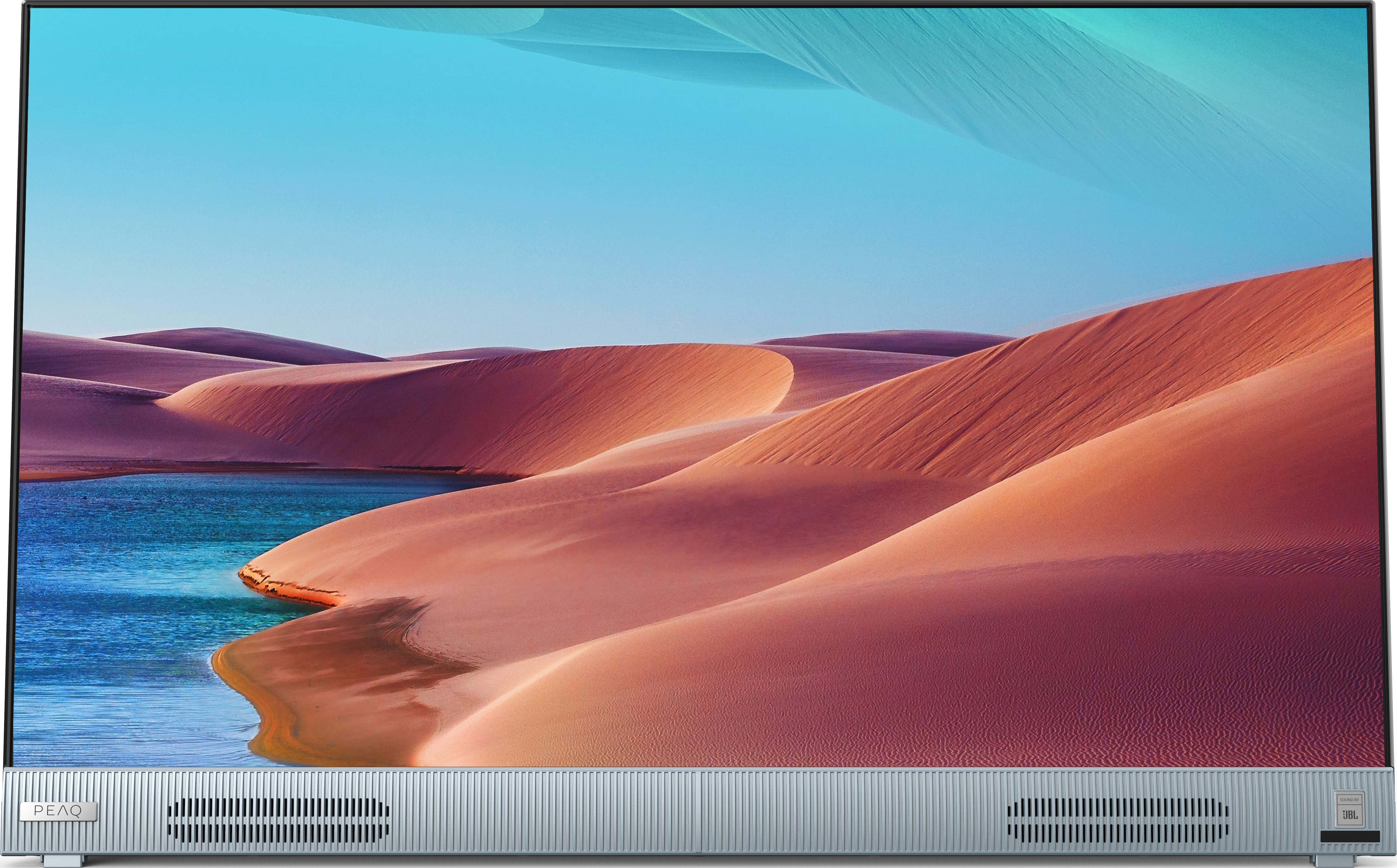 Ein großer Fernsehbildschirm zeigt eine Landschaft mit Sanddünen, blauem Himmel und Wasser.