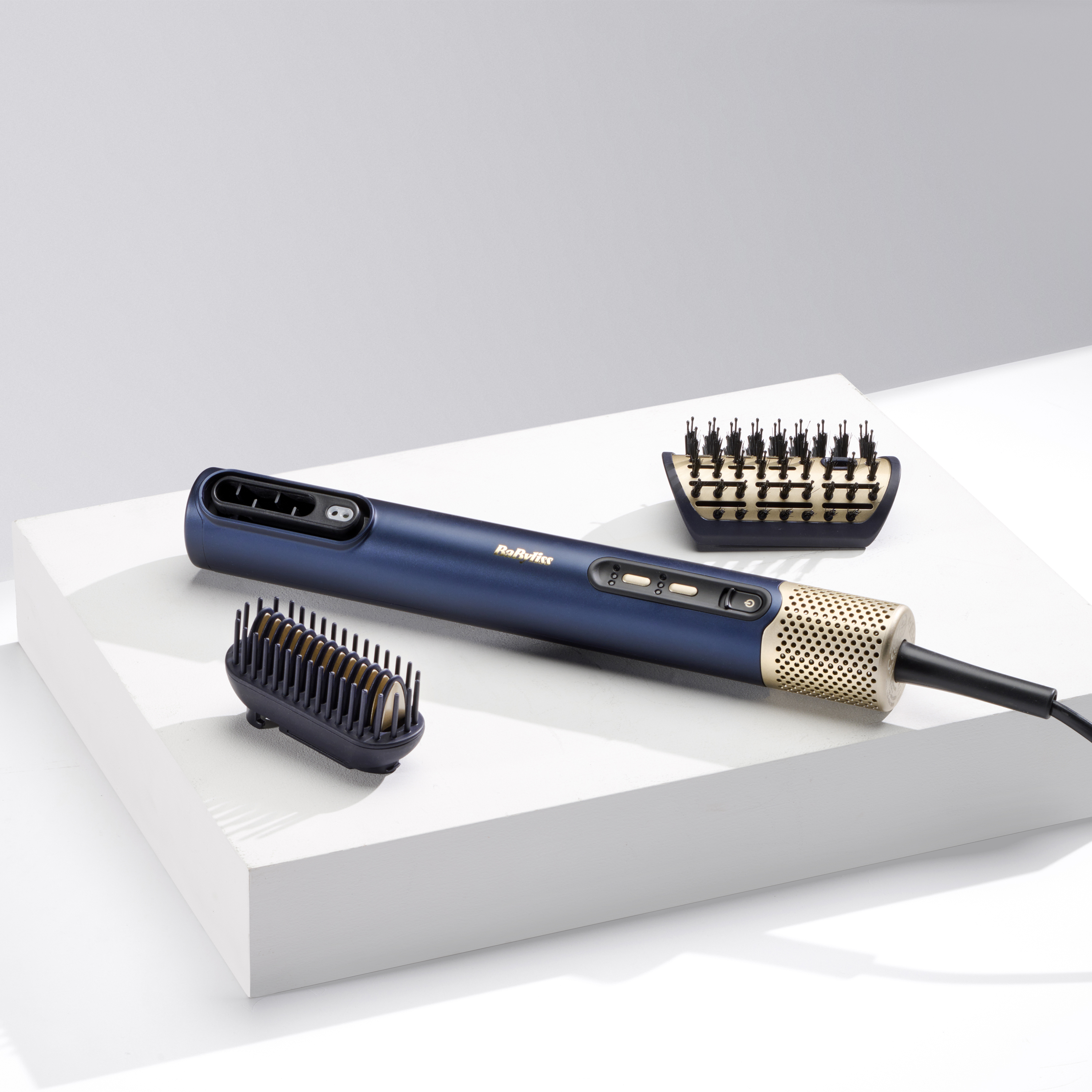 Herramienta para peinar el cabello con múltiples accesorios sobre una superficie blanca.