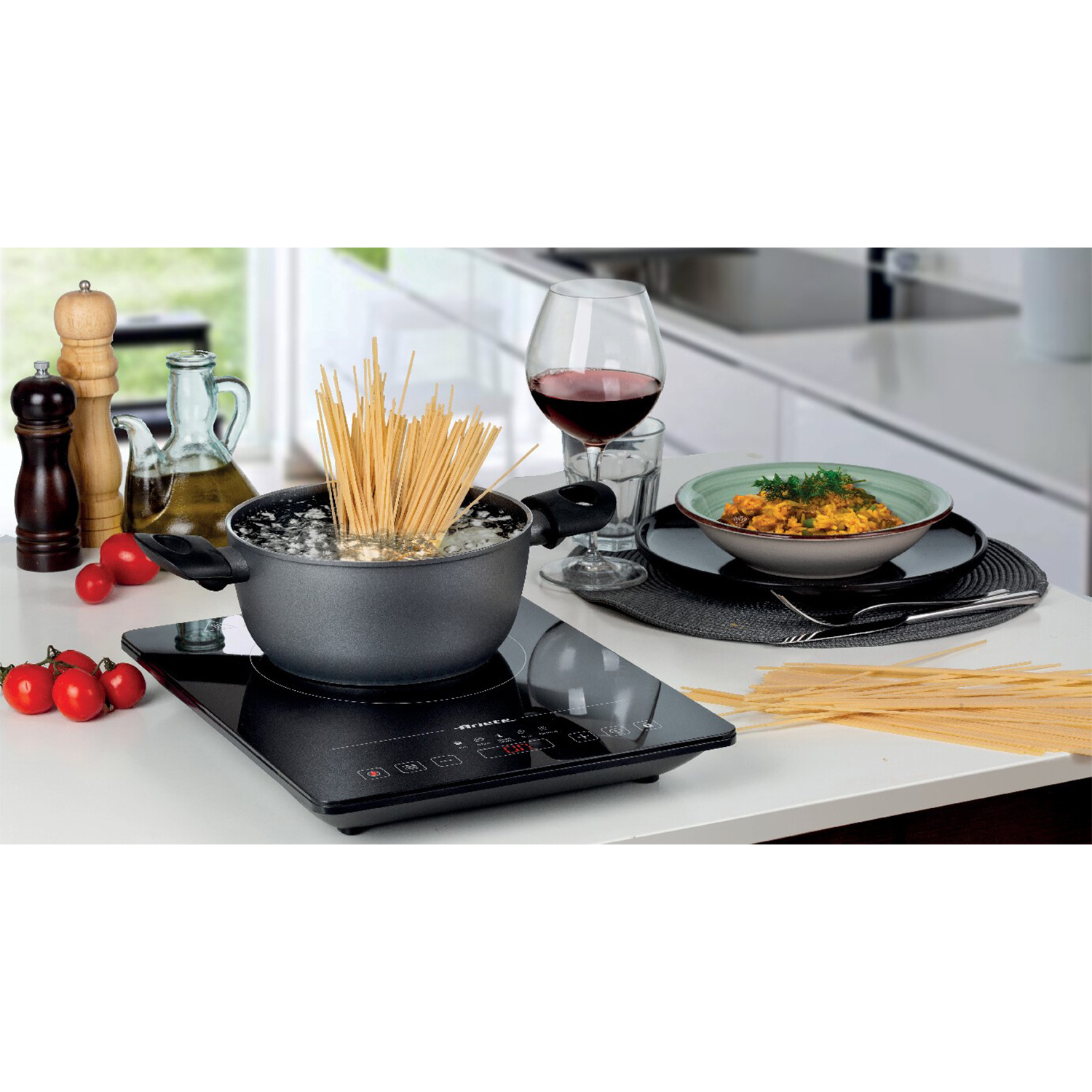 Pasta che cuoce in una pentola su un piano cottura a induzione, con altri piatti e ingredienti.
