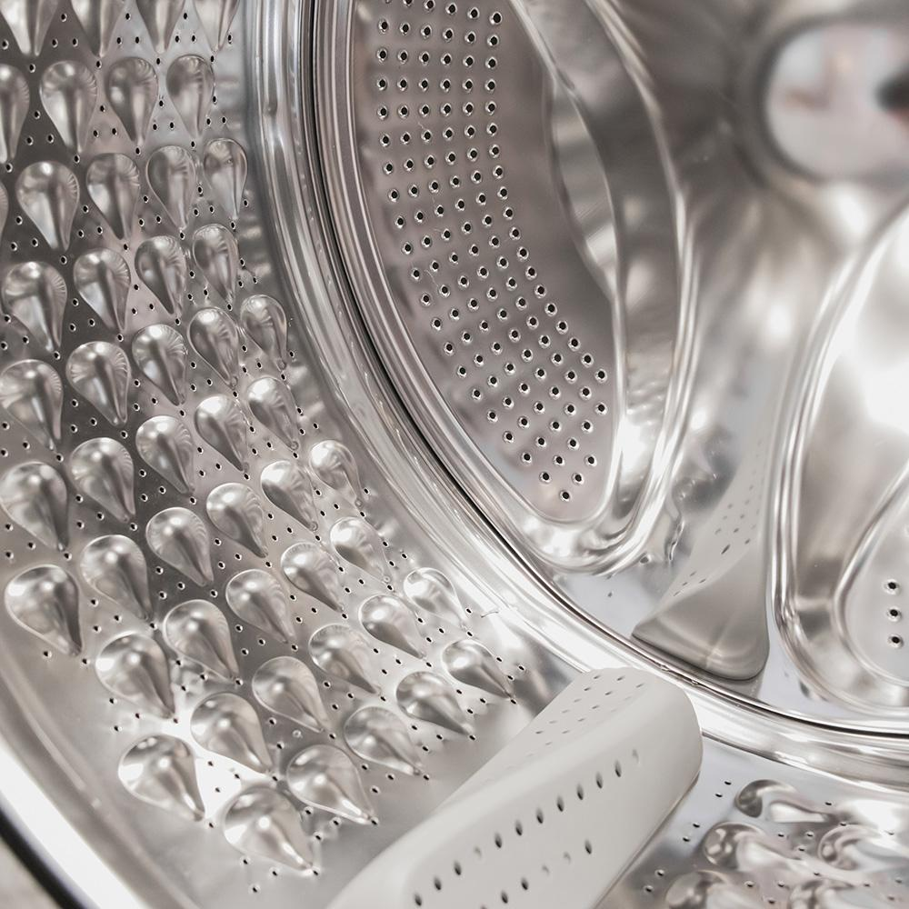 Primer plano del tambor de una lavadora con perforaciones en forma de gotas.