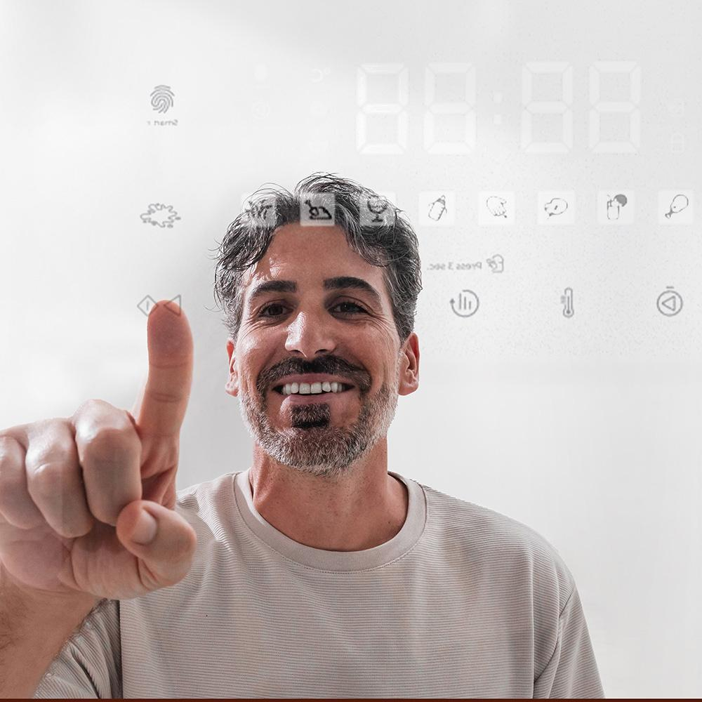 Hombre señalando una pared con iconos. Un hombre sonriente con pelo gris y barba.