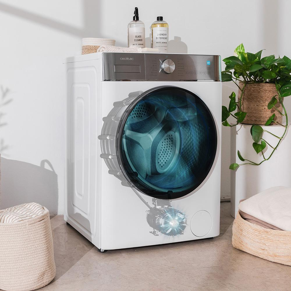 Lavadora blanca con ventana circular azul. Dos botellas arriba y plantas al fondo.