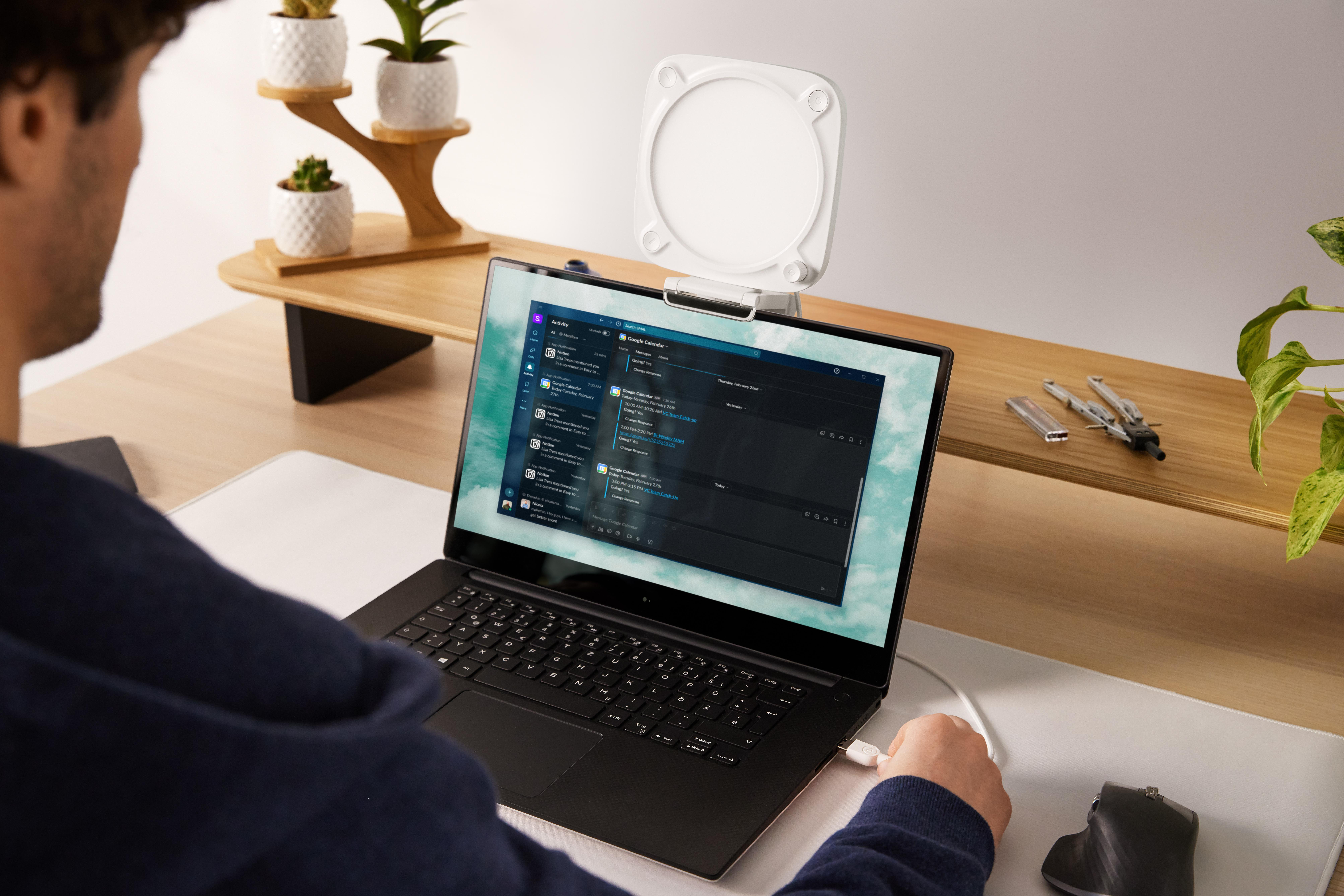 Eine Person benutzt einen Laptop mit einem Monitor. Hinter dem Monitor ist eine Schreibtischlampe.