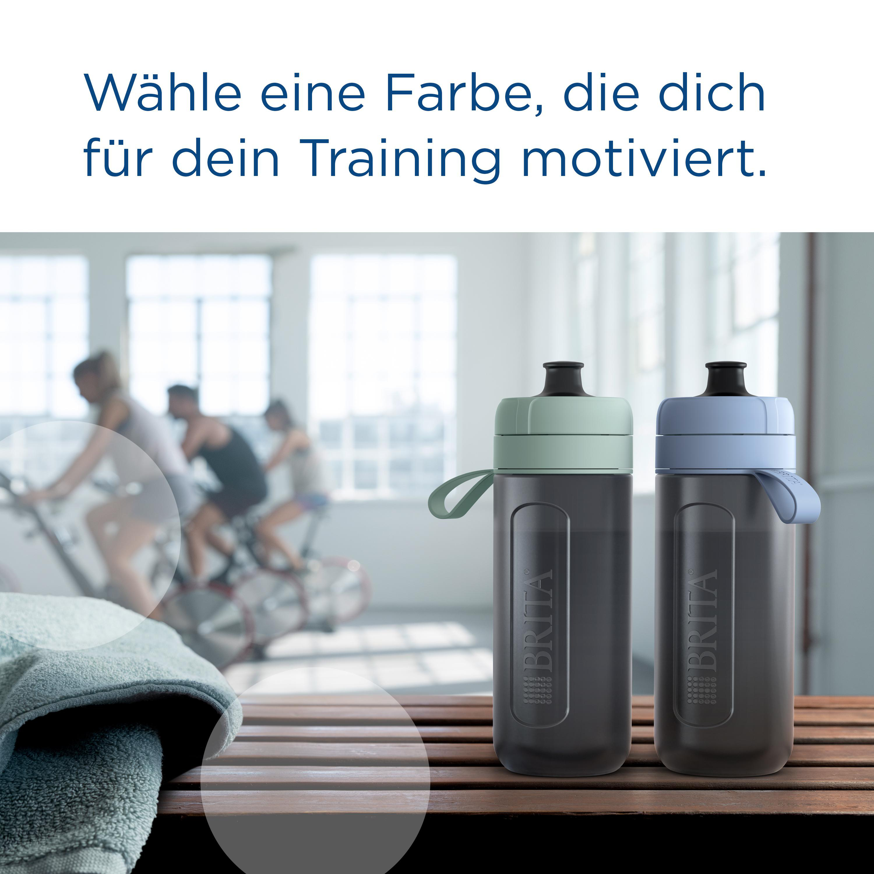 Zwei Wasserflaschen, eine grün, eine blau, auf einer Holzbank, mit Radfahrern im Hintergrund.
