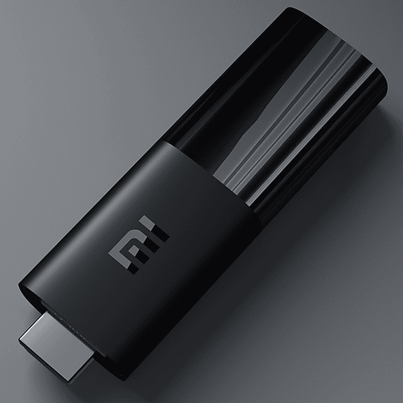 Fekete Mi TV Stick szürke felületen. A Mi logója látható.