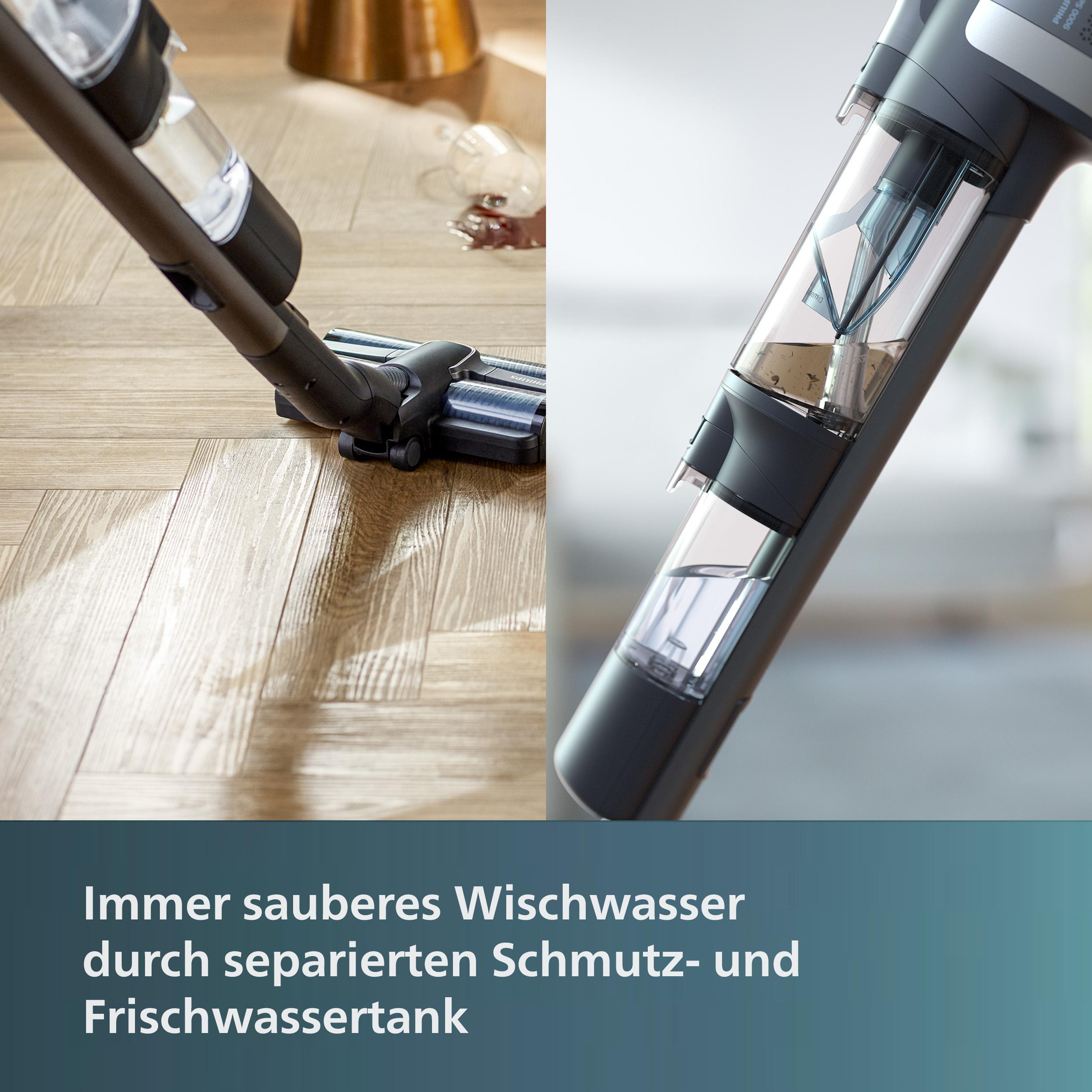 Staubsauger auf Holzboden. Ein Glas mit Flüssigkeit ist im Hintergrund verschüttet.