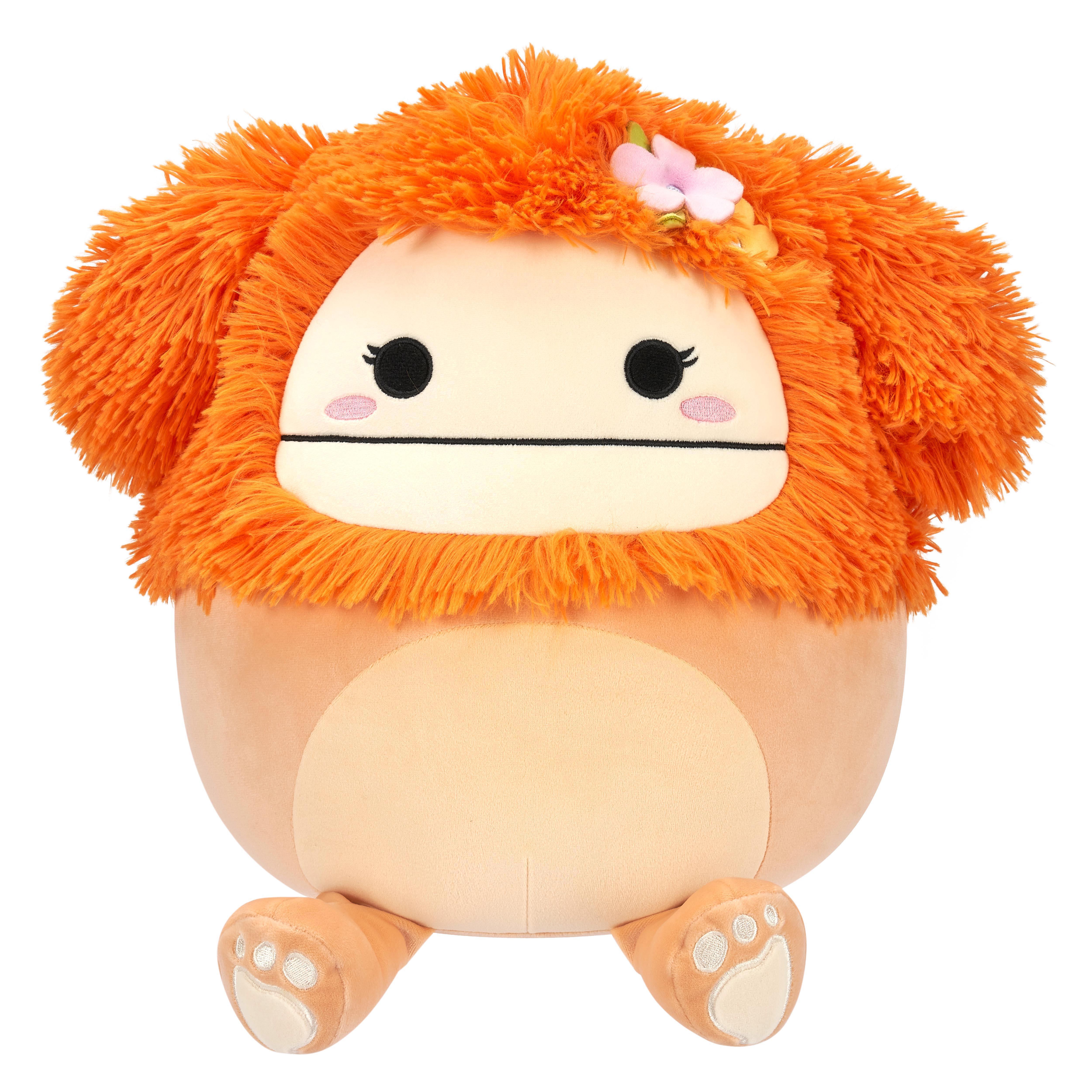 Orangenes, flauschiges Plüschtier mit Gesicht und kleiner Blume auf dem Kopf, sitzend.