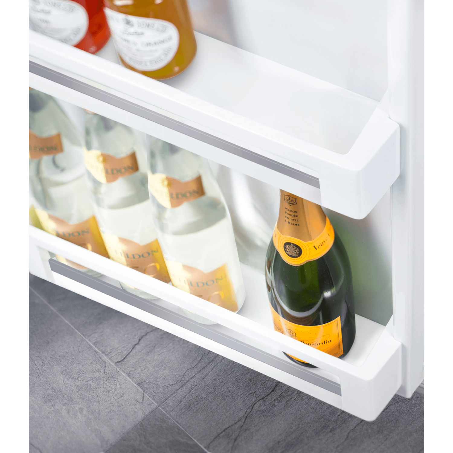 Refrigerator interior with champagne bottles on shelves. Shows the bottles in a cooling environment.