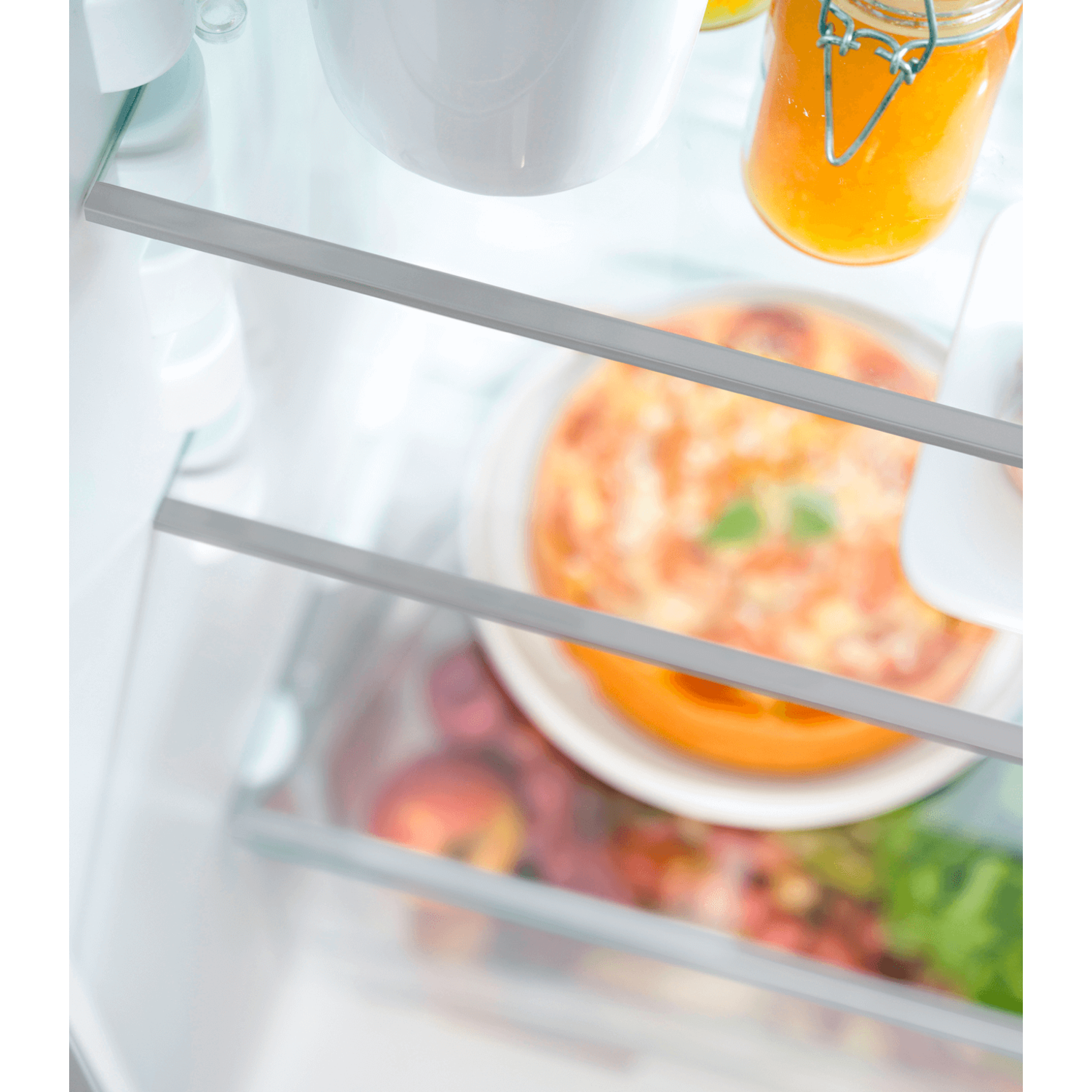 A refrigerator interior with shelves holding a jar, a plate of food, and other items.
