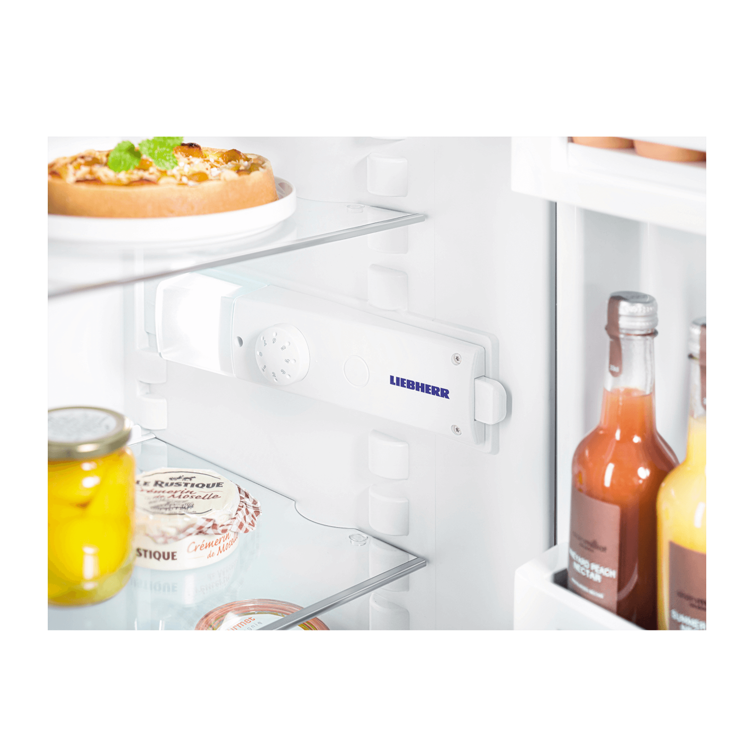 Refrigerator interior with shelves and contents. Includes jars, bottles, and a white control panel.