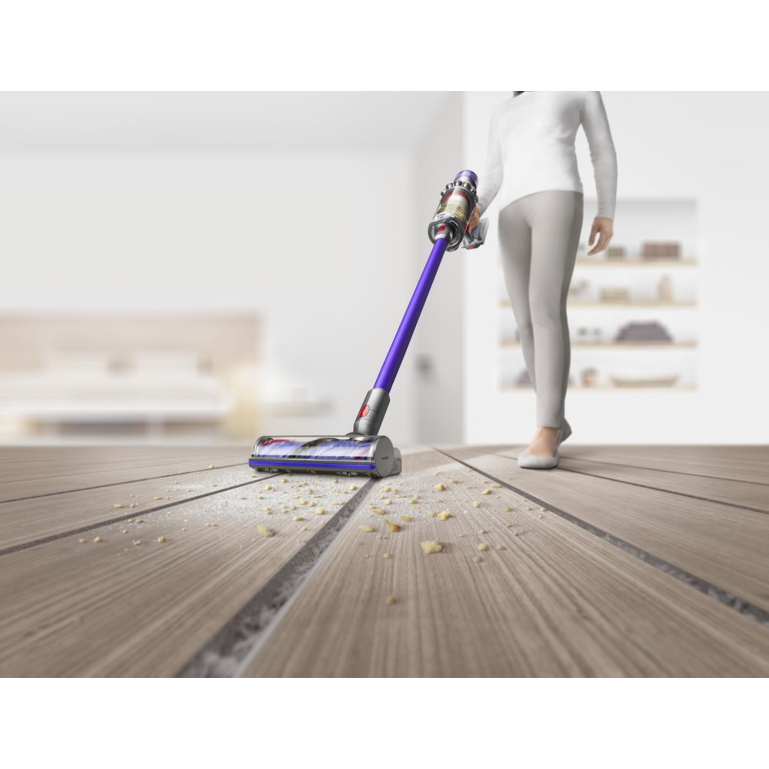 Woman vacuuming a wooden floor. The vacuum cleaner is purple and gray.