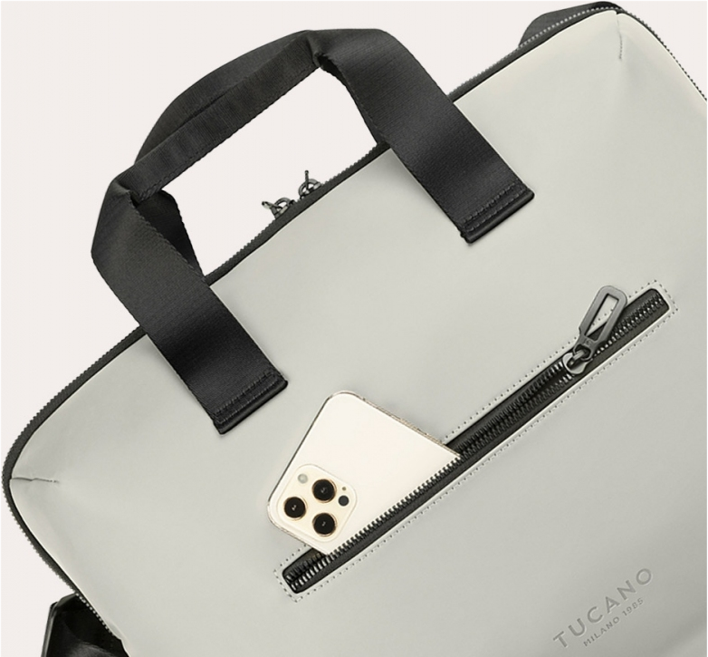 Primo piano di una borsa con telefono in tasca. Manico e cerniera neri, colore grigio chiaro.
