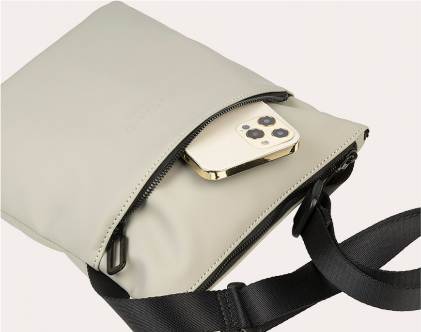 Una borsa a tracolla grigio chiaro con un telefono dorato che spunta dalla tasca.