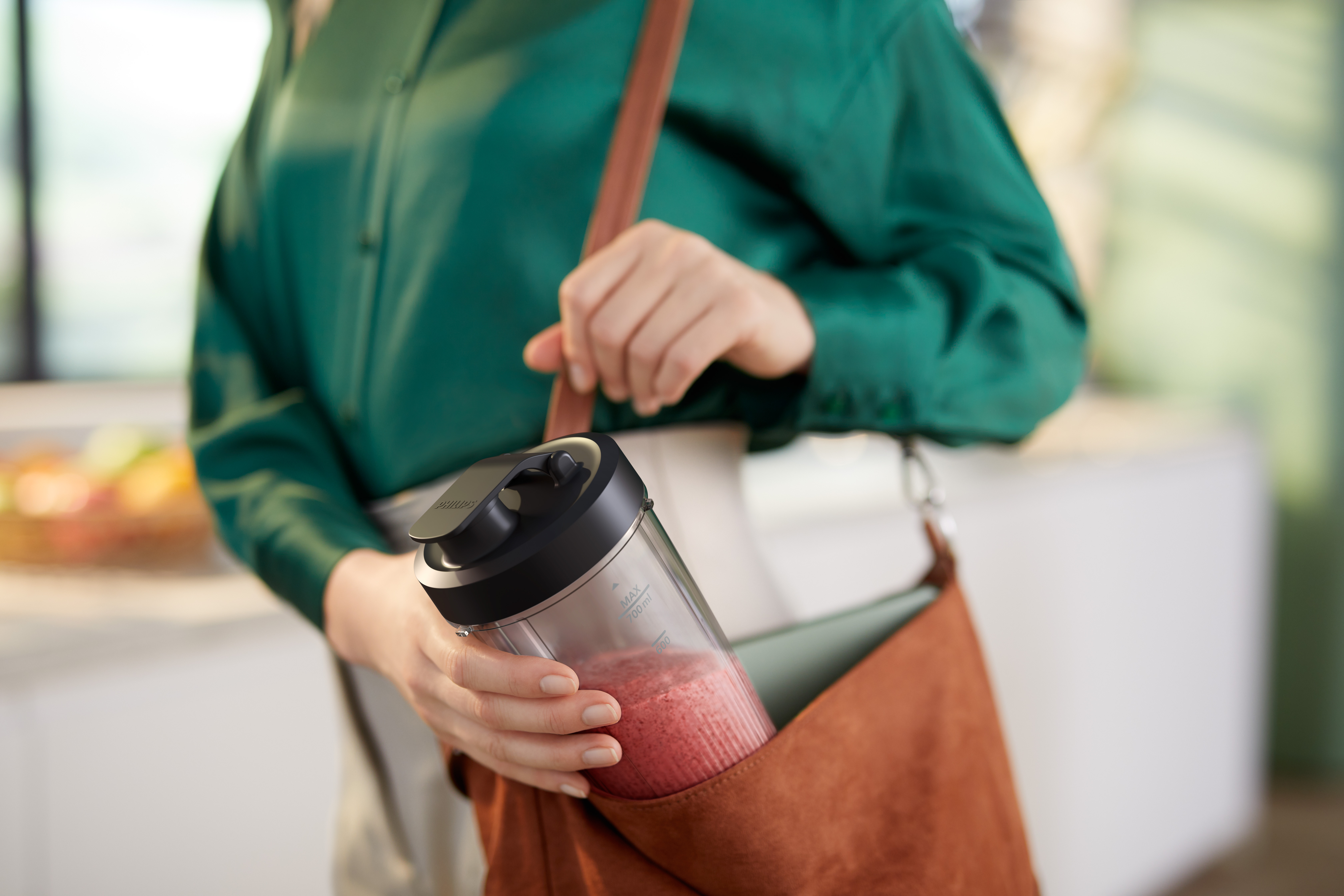 Una mujer sosteniendo una botella de licuadora en una bolsa marrón.
