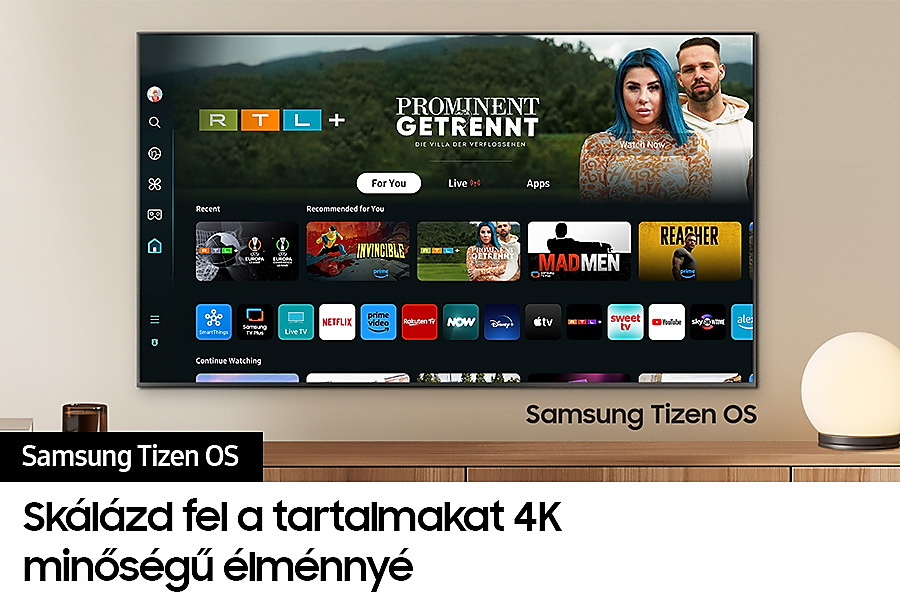 Egy TV képernyő egy programot jelenít meg. A TV egy fa állványon van. Szöveg a képen.