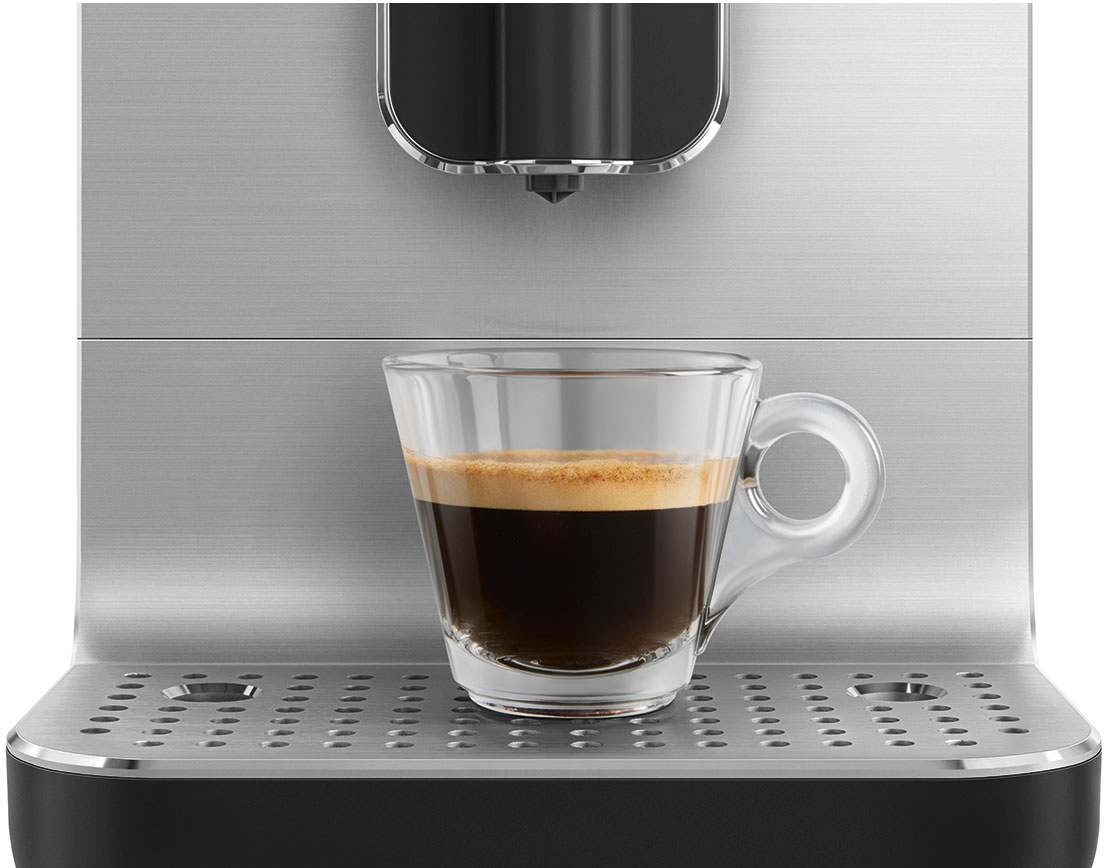 Un espresso in una tazza di vetro trasparente è posato su una macchina da caffè. La macchina è argentata.