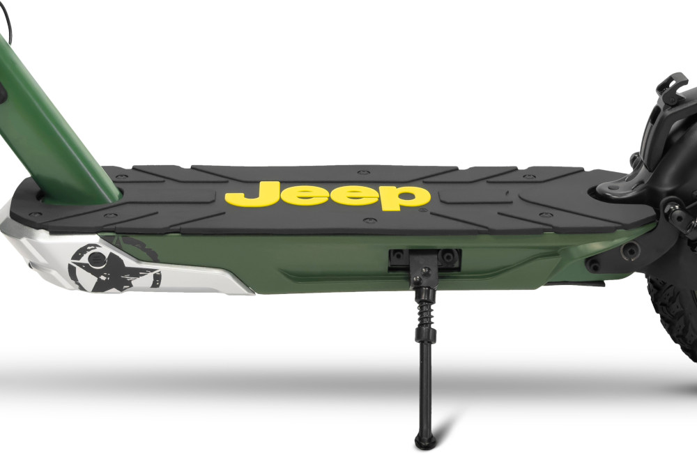 Close-up van de voetsteun van een Jeep elektrische scooter. Groen en zwart met geel logo. Witte achtergrond.