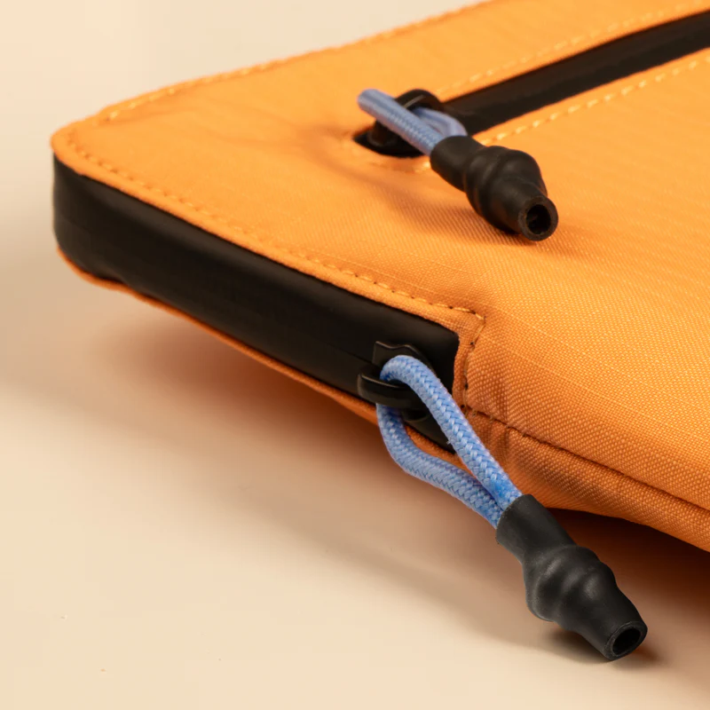 Eine orangefarbene Tasche mit schwarzen Akzenten. Ein blaues Kabel mit schwarzen Spitzen, Nahaufnahme.