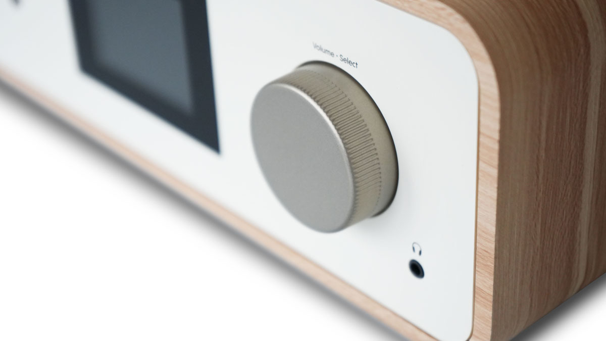 Nahaufnahme eines Holzradios mit silbernem Knopf. Weißes Panel mit kleinem Bildschirm.