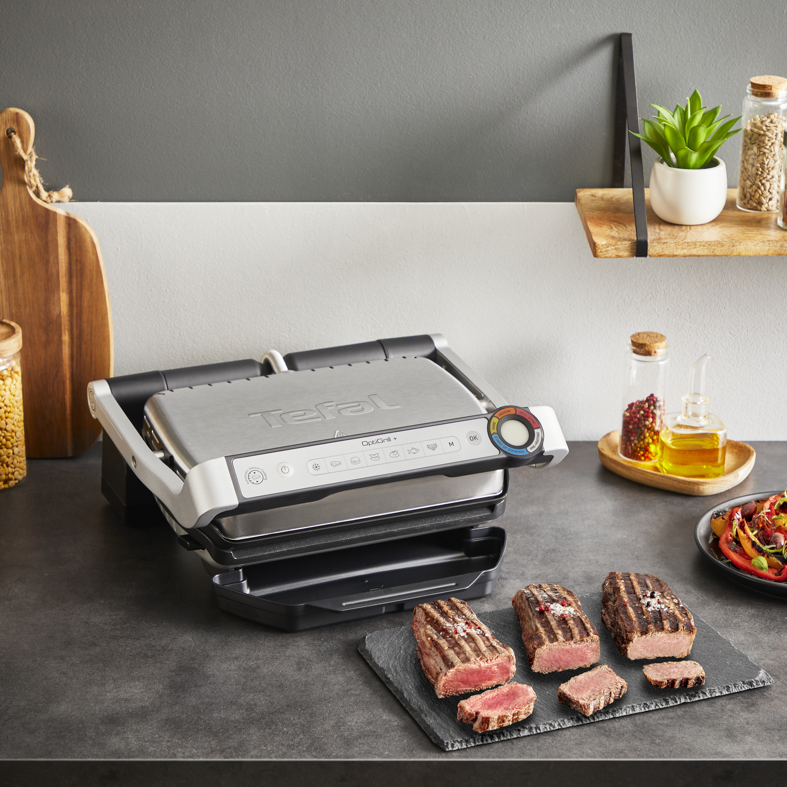 Tefal OptiGrill+ sült steakkel, zöldségekkel és fűszerekkel a pulton. Látható összetevők.