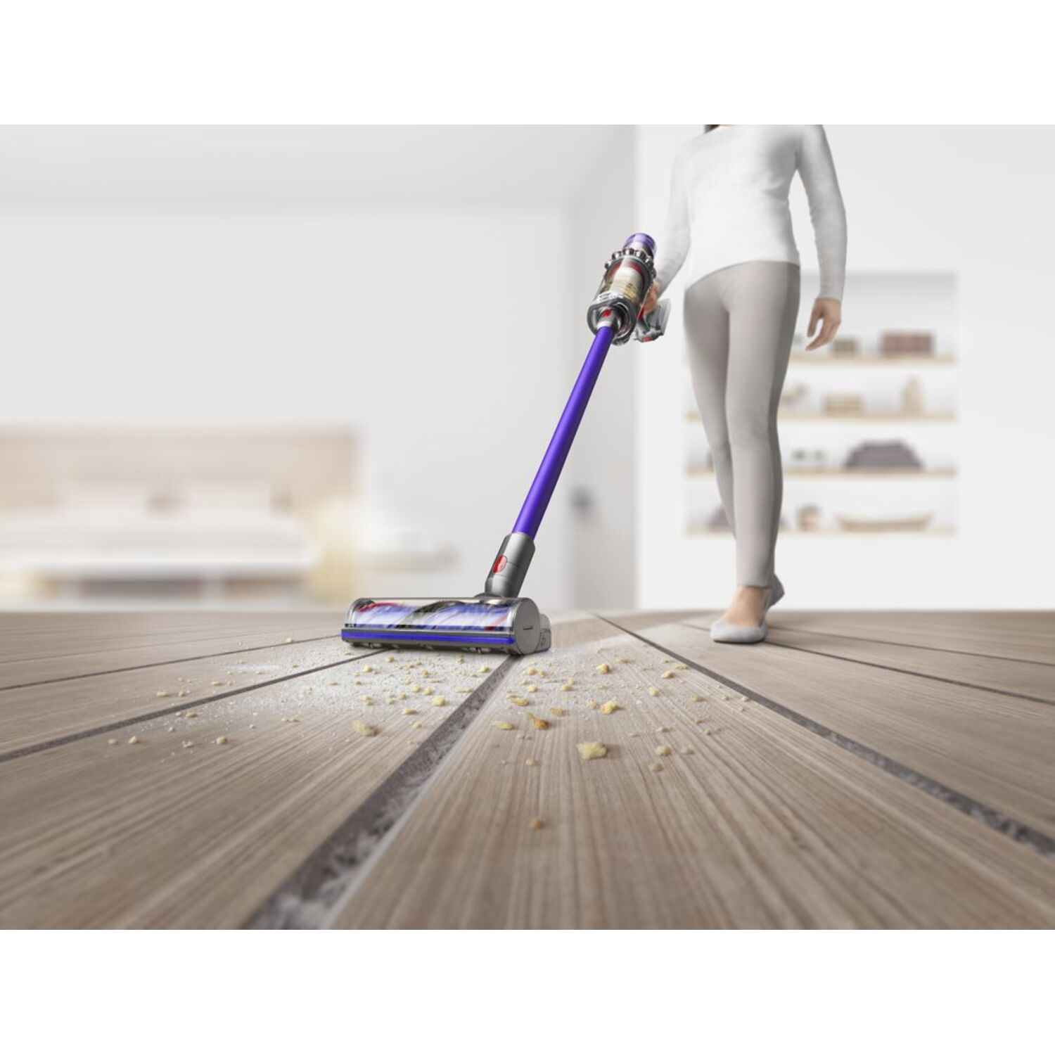 Femme passant l'aspirateur sur un sol en bois avec un aspirateur Dyson violet et argent.