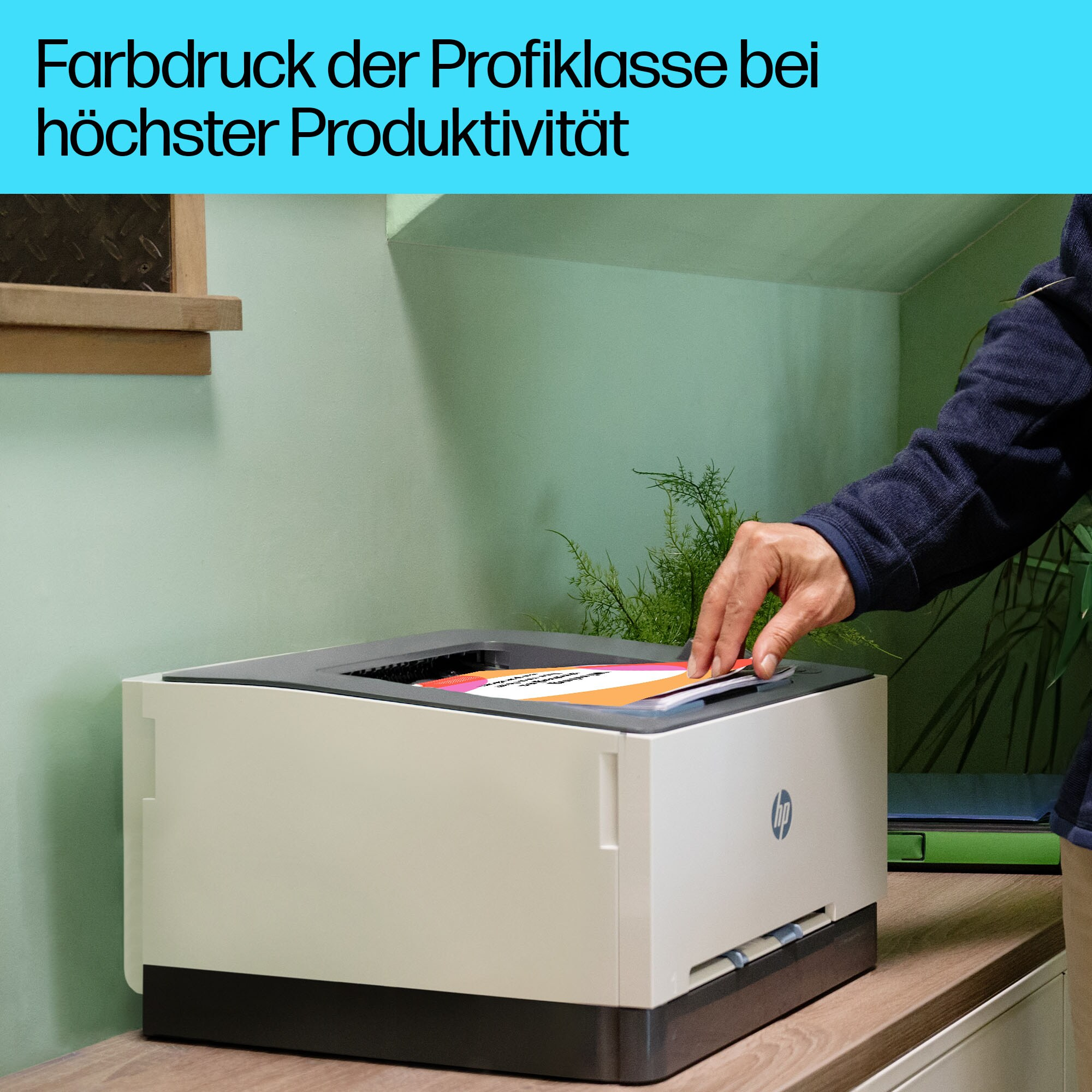 Eine Person benutzt einen Drucker, das Ausgabefach ist geöffnet, und Text auf Deutsch oben.