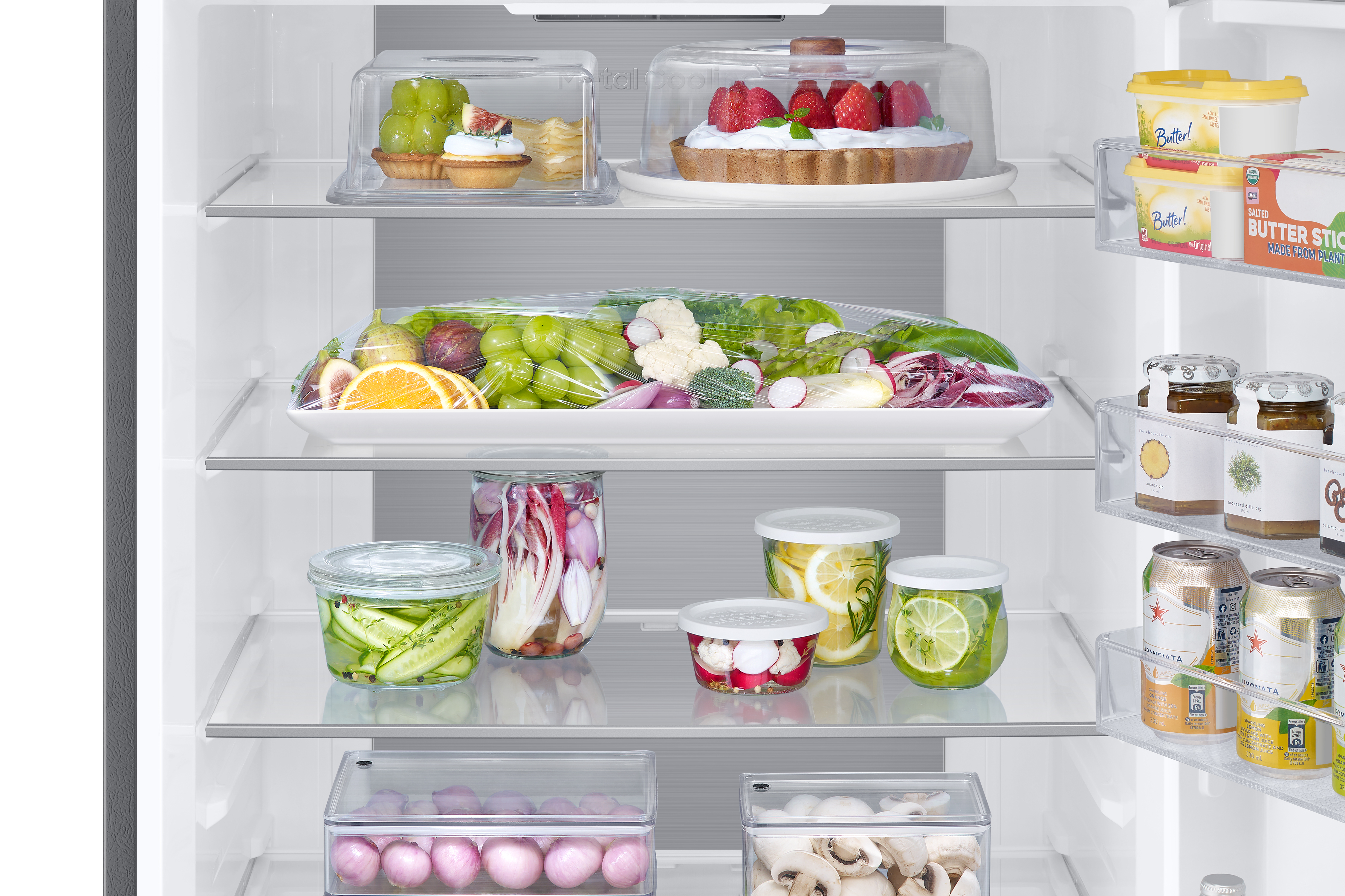 Kühlschrankinnenraum mit Regalen mit verschiedenen Lebensmitteln, darunter Obst und Gemüse.