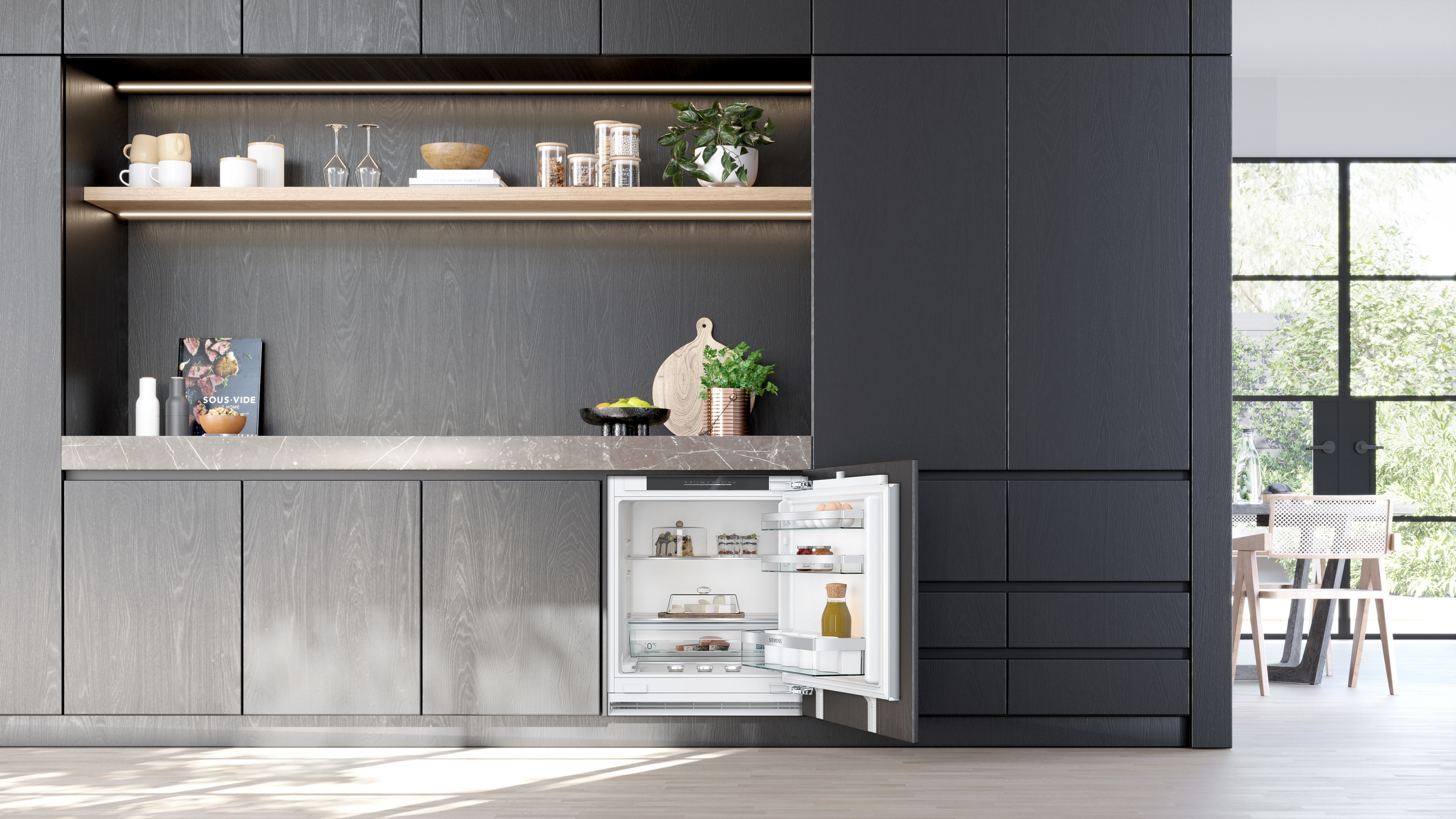 Eine moderne Küche mit dunklen Holzschränken, einem offenen Kühlschrank und einer gut beleuchteten Arbeitsplatte mit Deko.