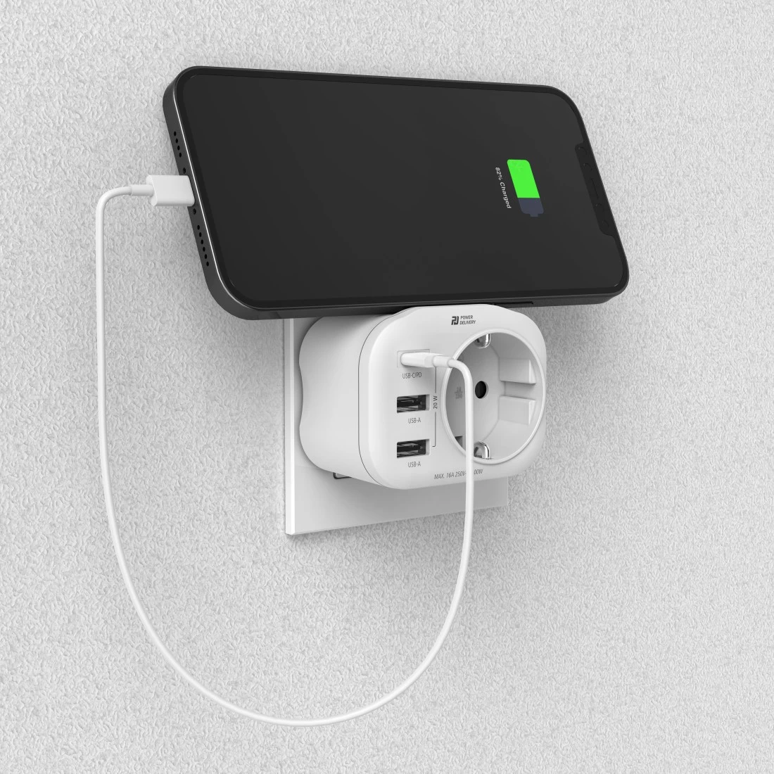 Telefon ładujący się na adapterze podłączonym do ściany, pokazujący naładowanie baterii.