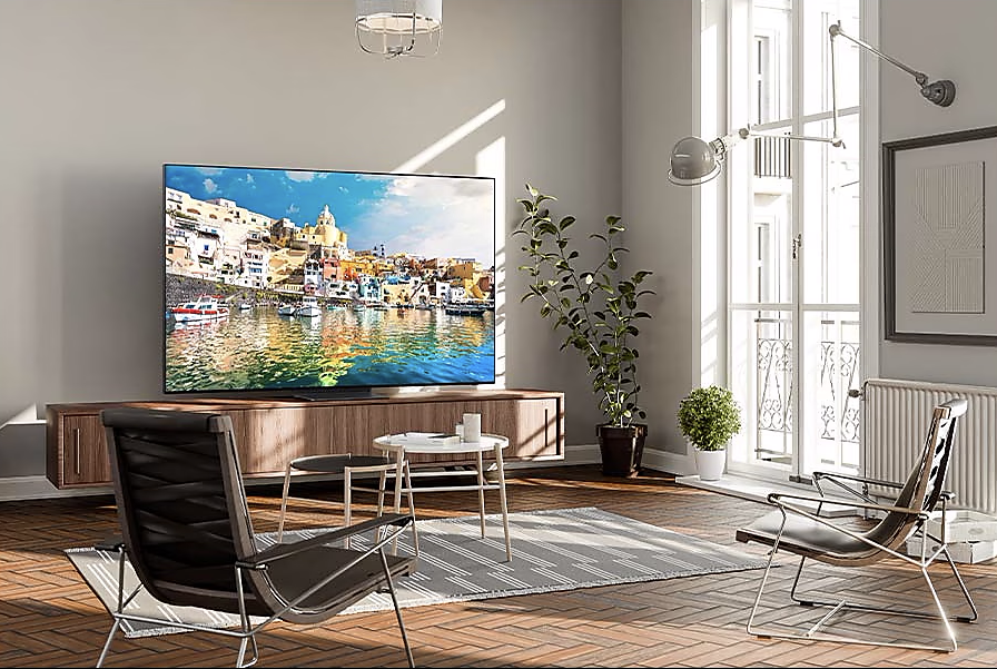 Nappali nagy TV-vel, színes képpel. Bútorok és ablak is látható.