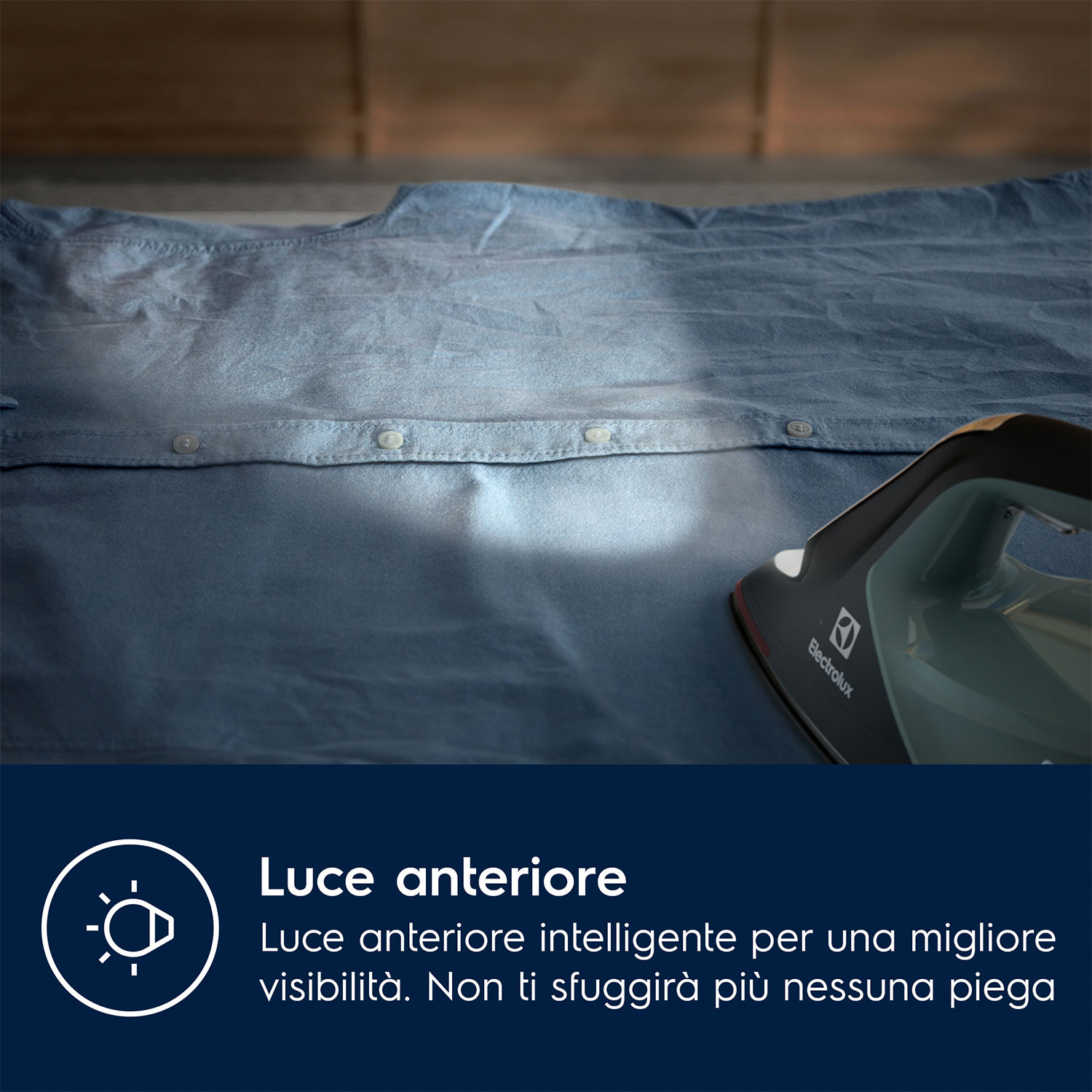 Stiratura di una camicia blu. Ferro da stiro a destra, fascio di luce sulla camicia. Testo descrive la luce.