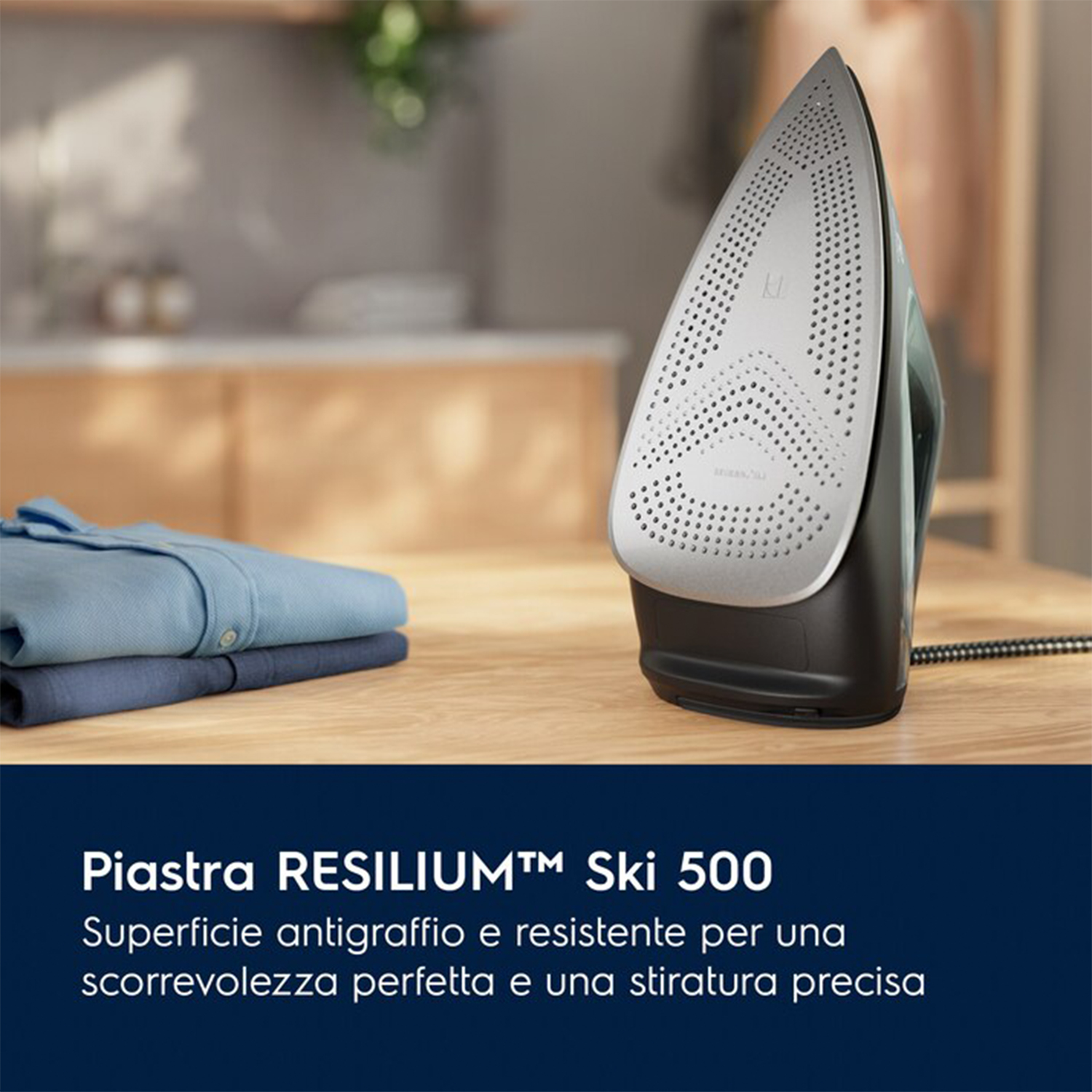 Un ferro da stiro è su un tavolo di legno accanto a camicie piegate. Il ferro è nero e grigio.
