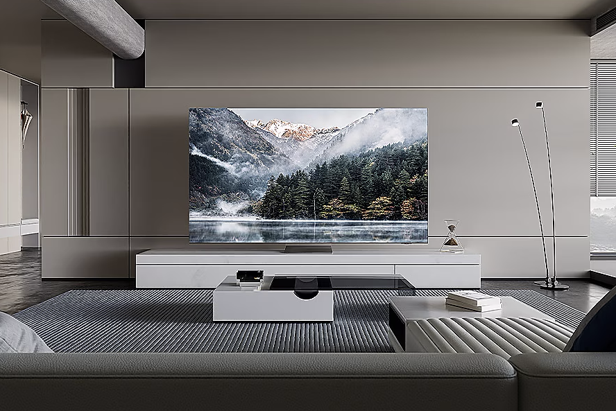 Nappali TV-vel. Egy nagy TV fehér állványon, egy szürke kanapé és modern esztétika.