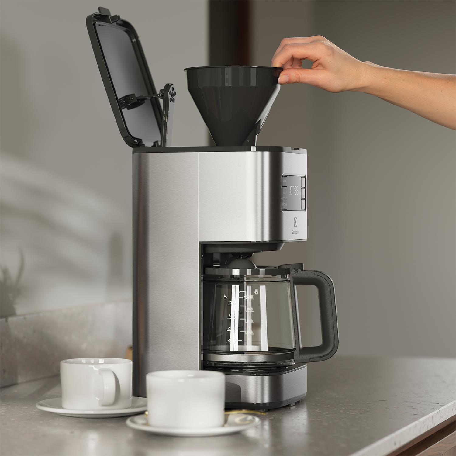 Una caffettiera argentata con una mano che aggiunge caffè macinato.