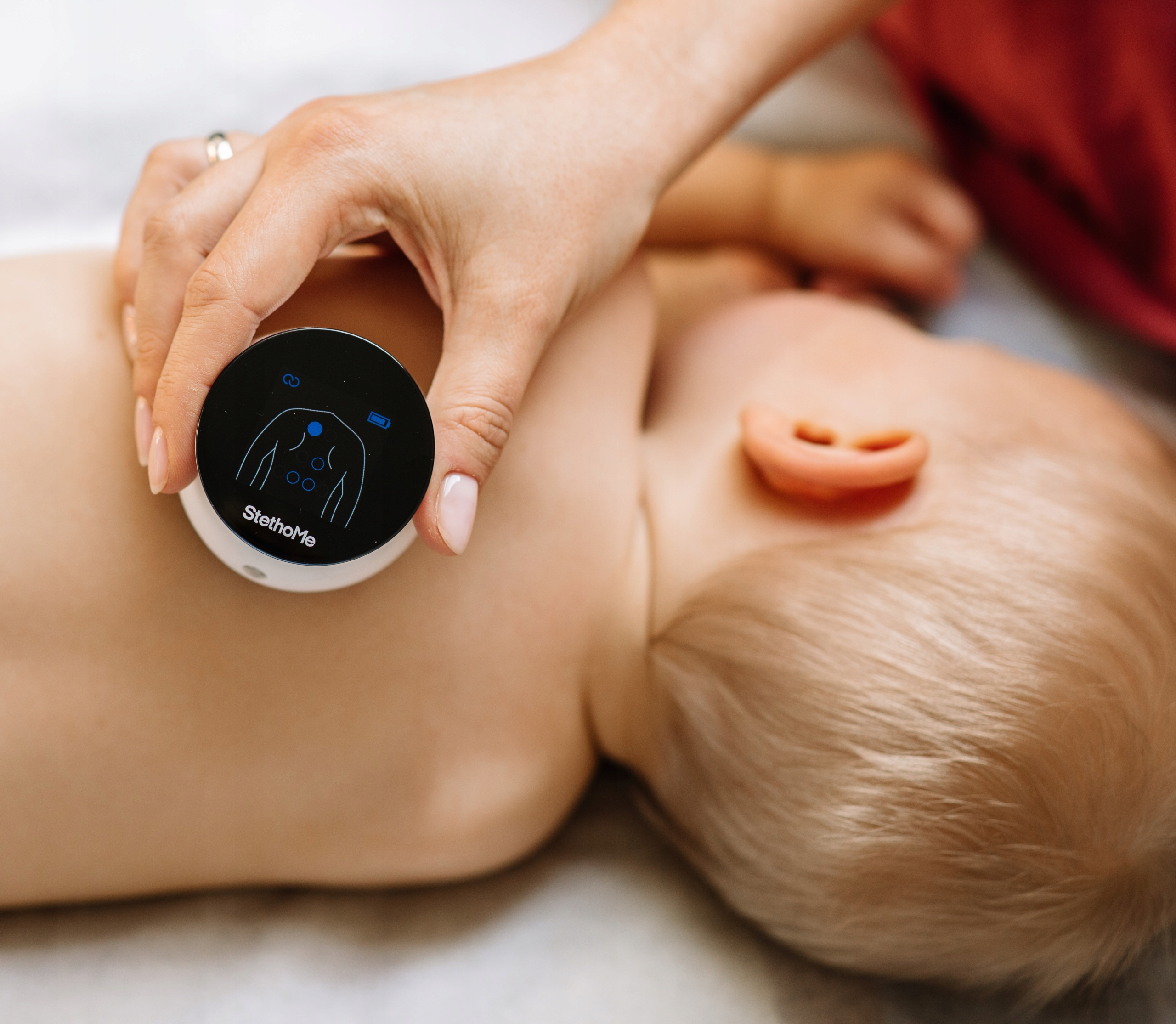 Ręka osoby trzymająca stetoskop na klatce piersiowej dziecka.