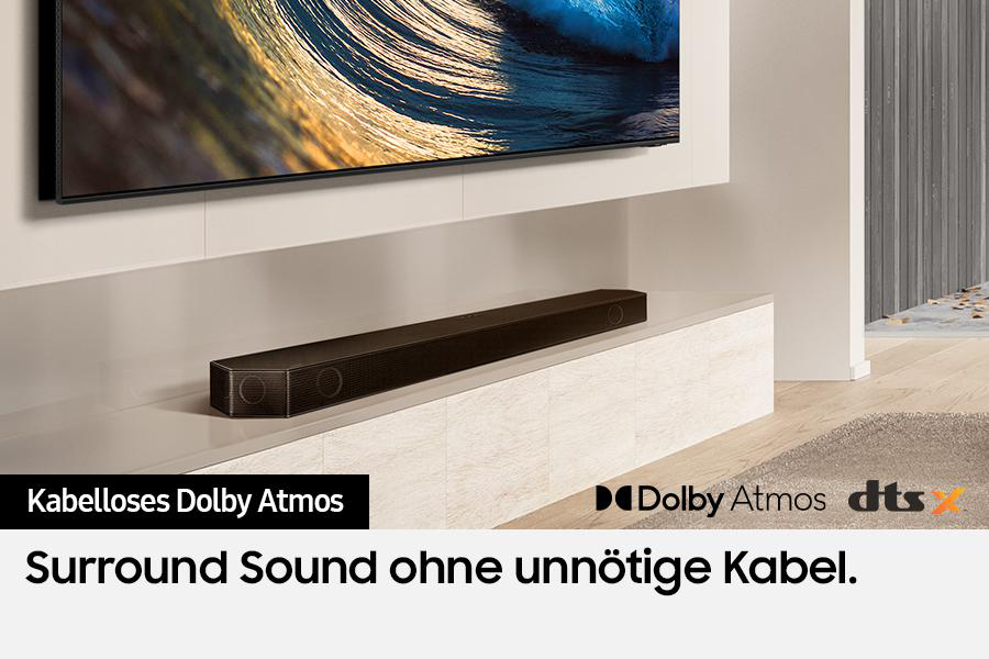 Eine schwarze Soundbar auf einer weißen Oberfläche mit einem modernen Fernseher darüber.