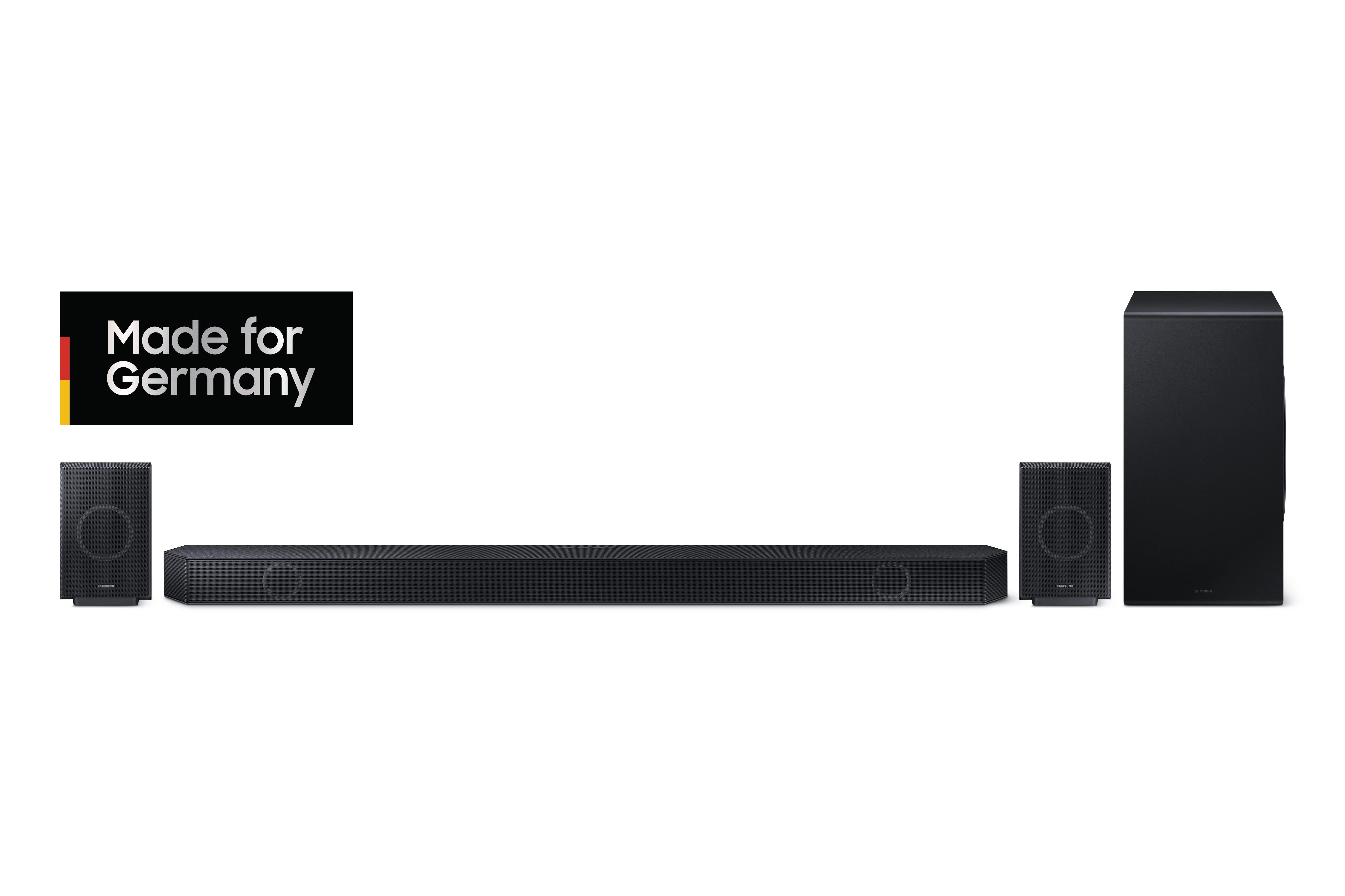 Schwarzes Samsung Soundbar- und Subwoofer-Set mit zwei Satellitenlautsprechern vor weißem Hintergrund.