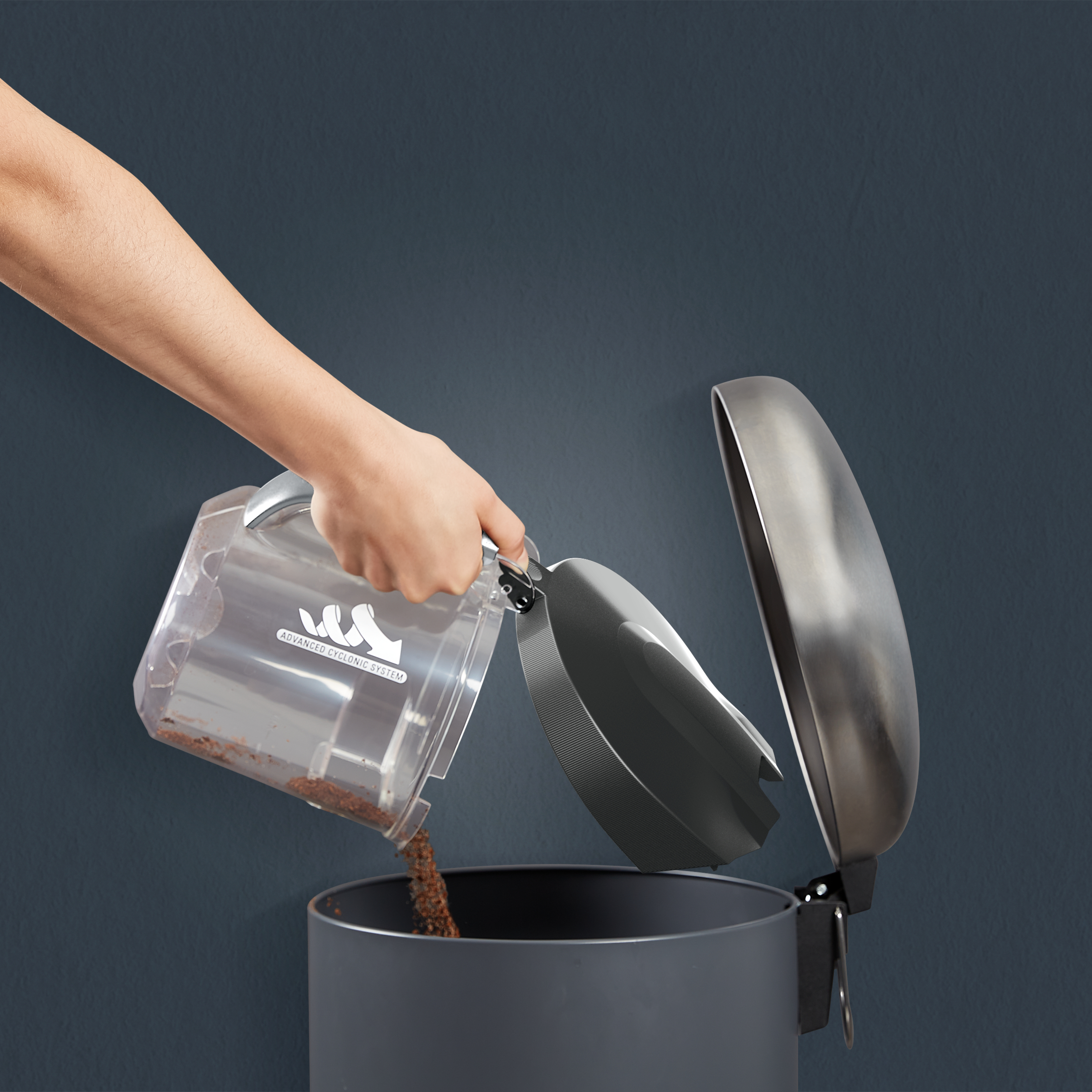 Ręka opróżniająca przezroczysty pojemnik z brudem do szarego kosza na śmieci. Ciemnoniebieskie tło.