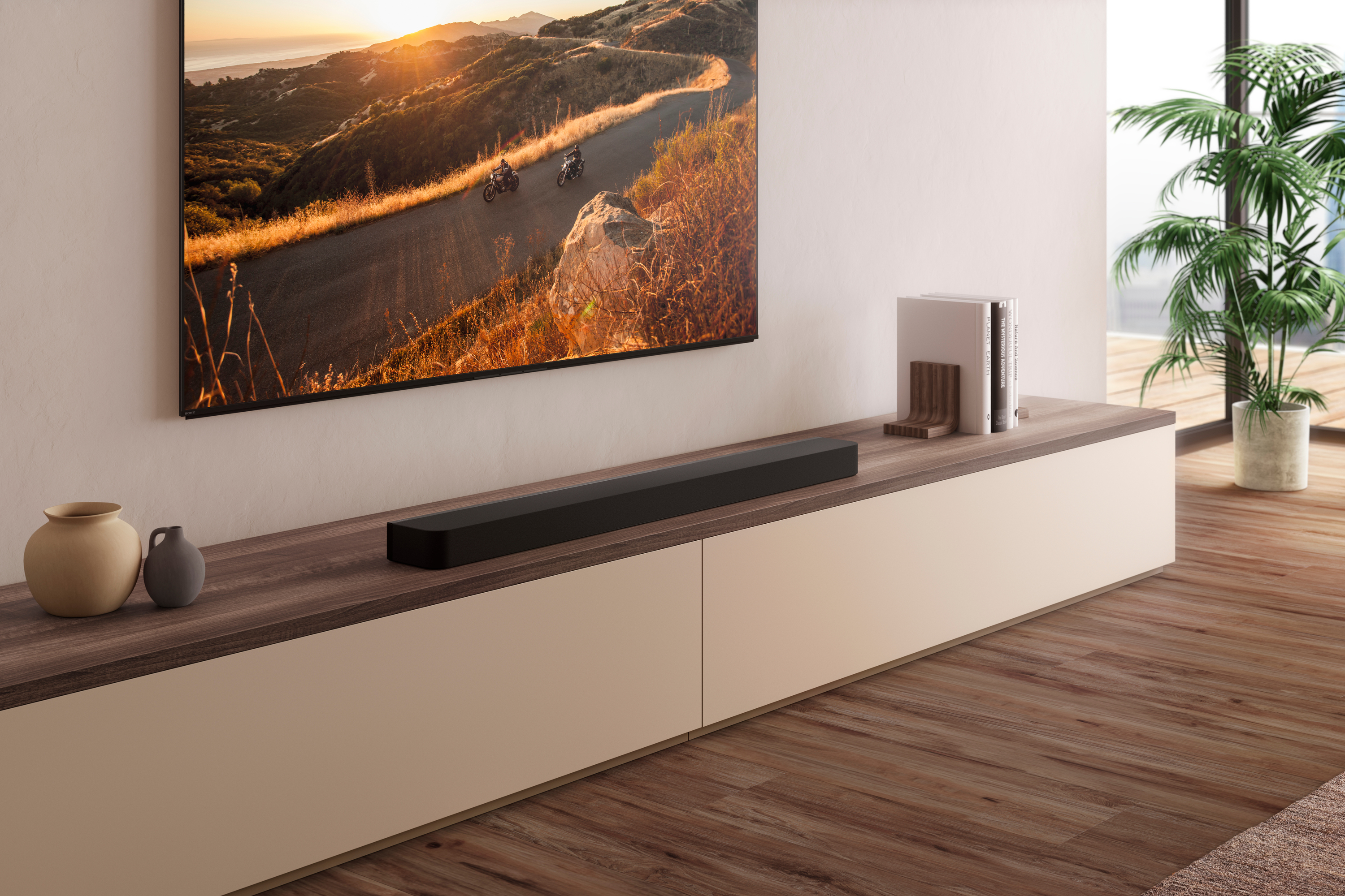 Salon avec TV et barre de son sur un meuble en bois, avec une grande fenêtre.