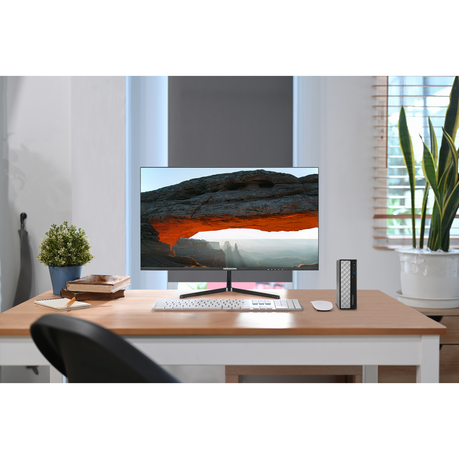 Een computeropstelling op een bureau. Een monitor toont een oranje canyonscène. Toetsenbord, muis en een kleine pc.