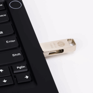 Silberner HP USB-Stick, der in einen schwarzen Laptop gesteckt ist, auf weißem Untergrund.