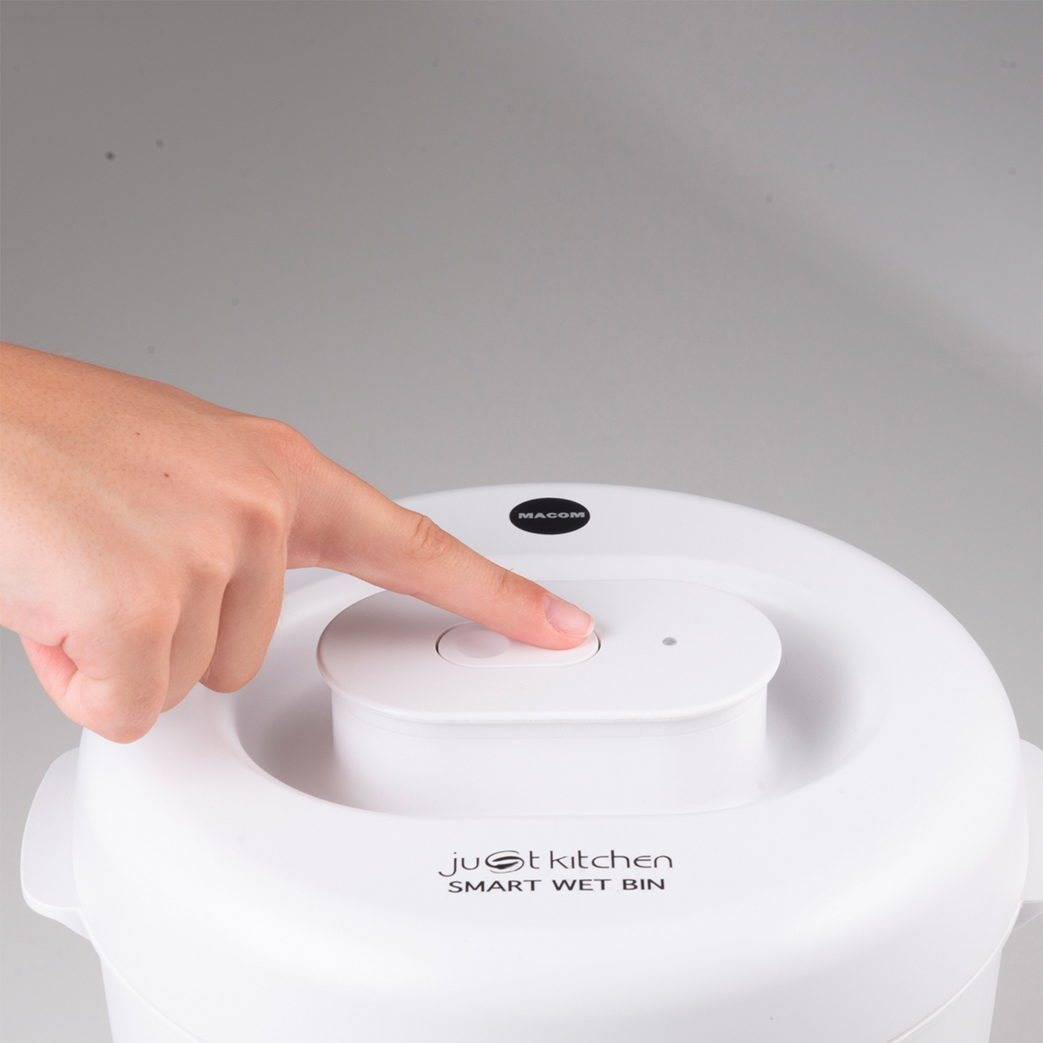 Mano che preme un pulsante su un 'just kitchen' Smart Wet Bin bianco.