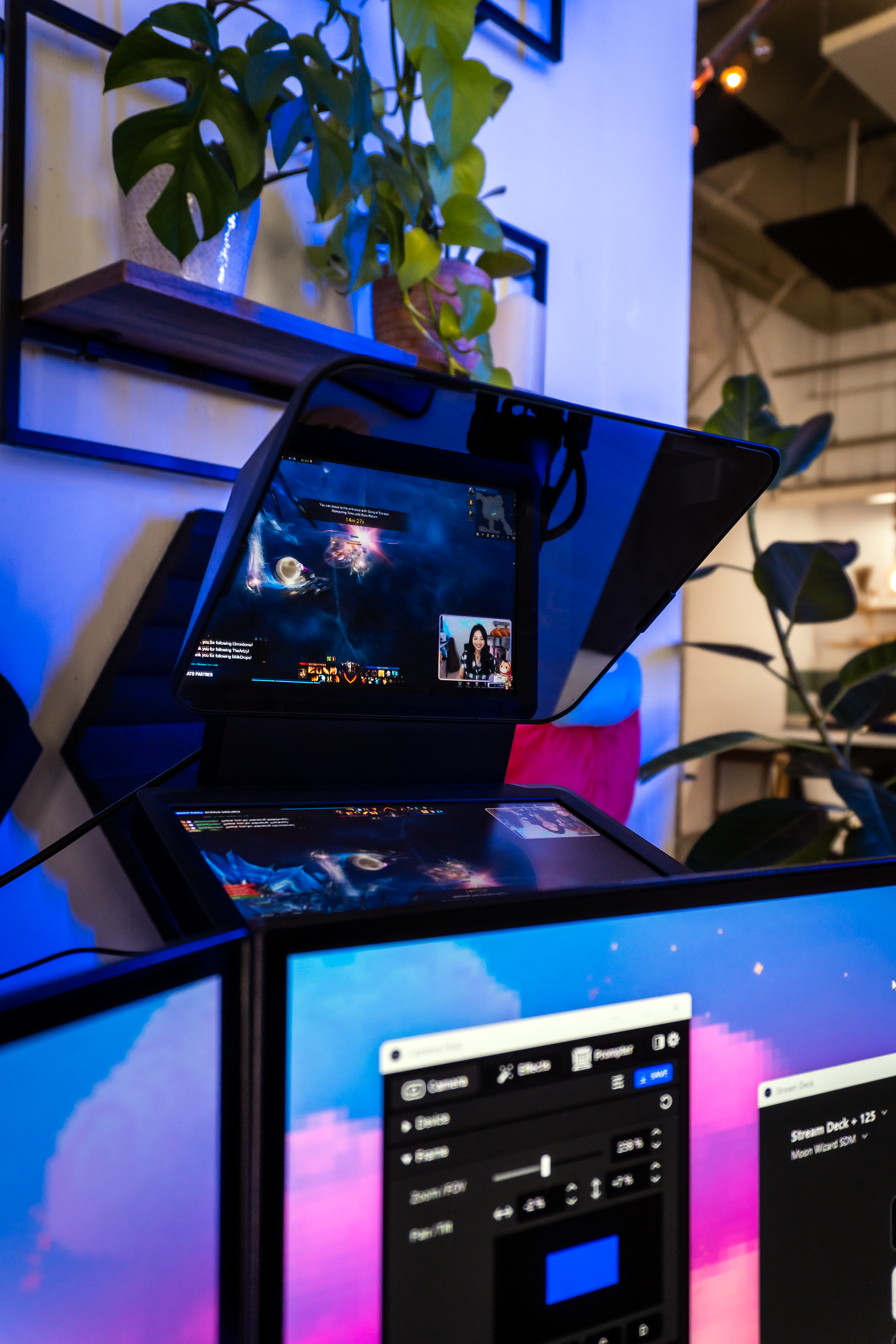 Ein Gaming-Setup mit mehreren Monitoren, einem Bildschirmschild und einer Person im Video-Feed.