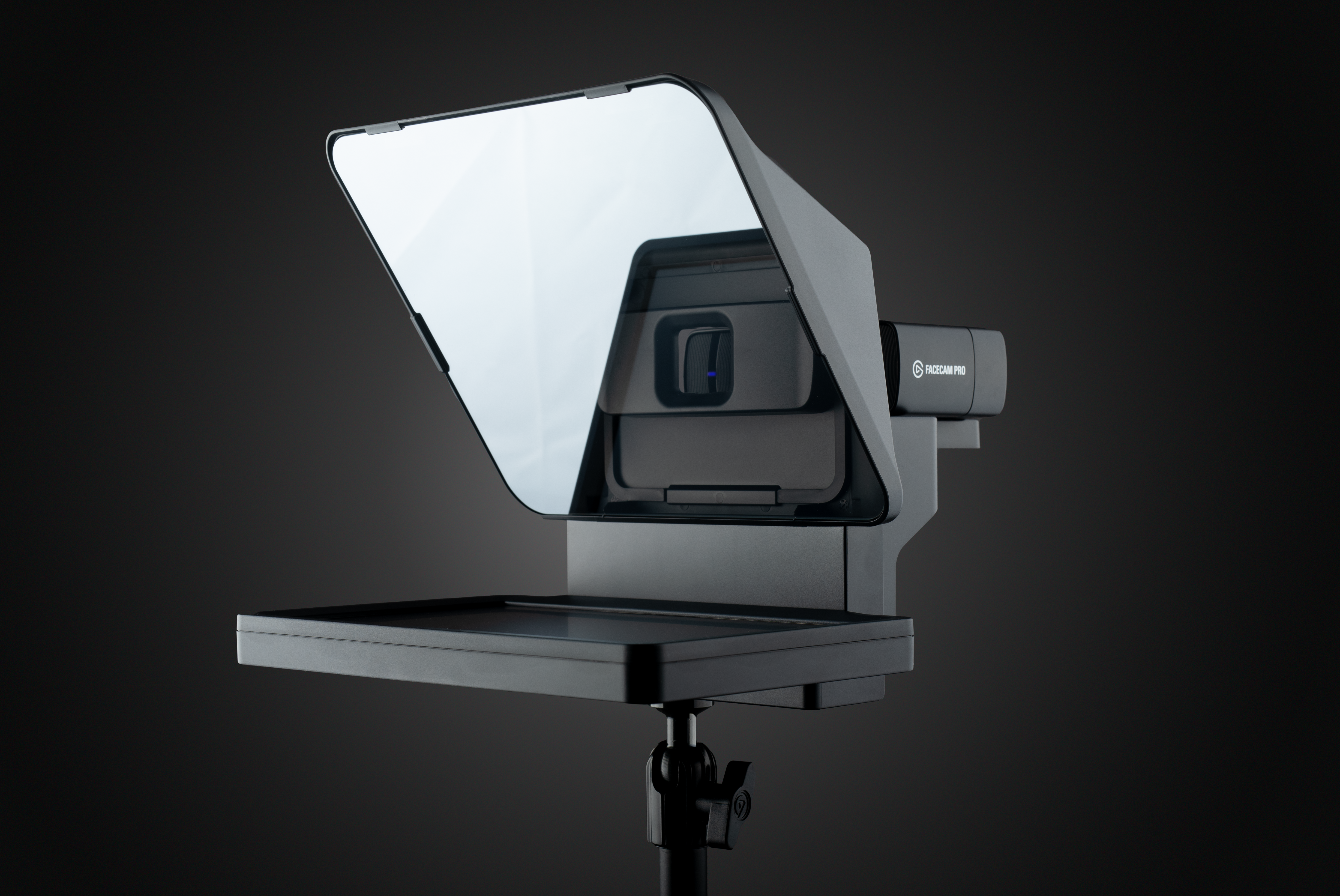 Ein schwarzer Facecam Pro Teleprompter mit reflektierendem Bildschirm, montiert auf einem Stativ, vor dunklem Hintergrund.