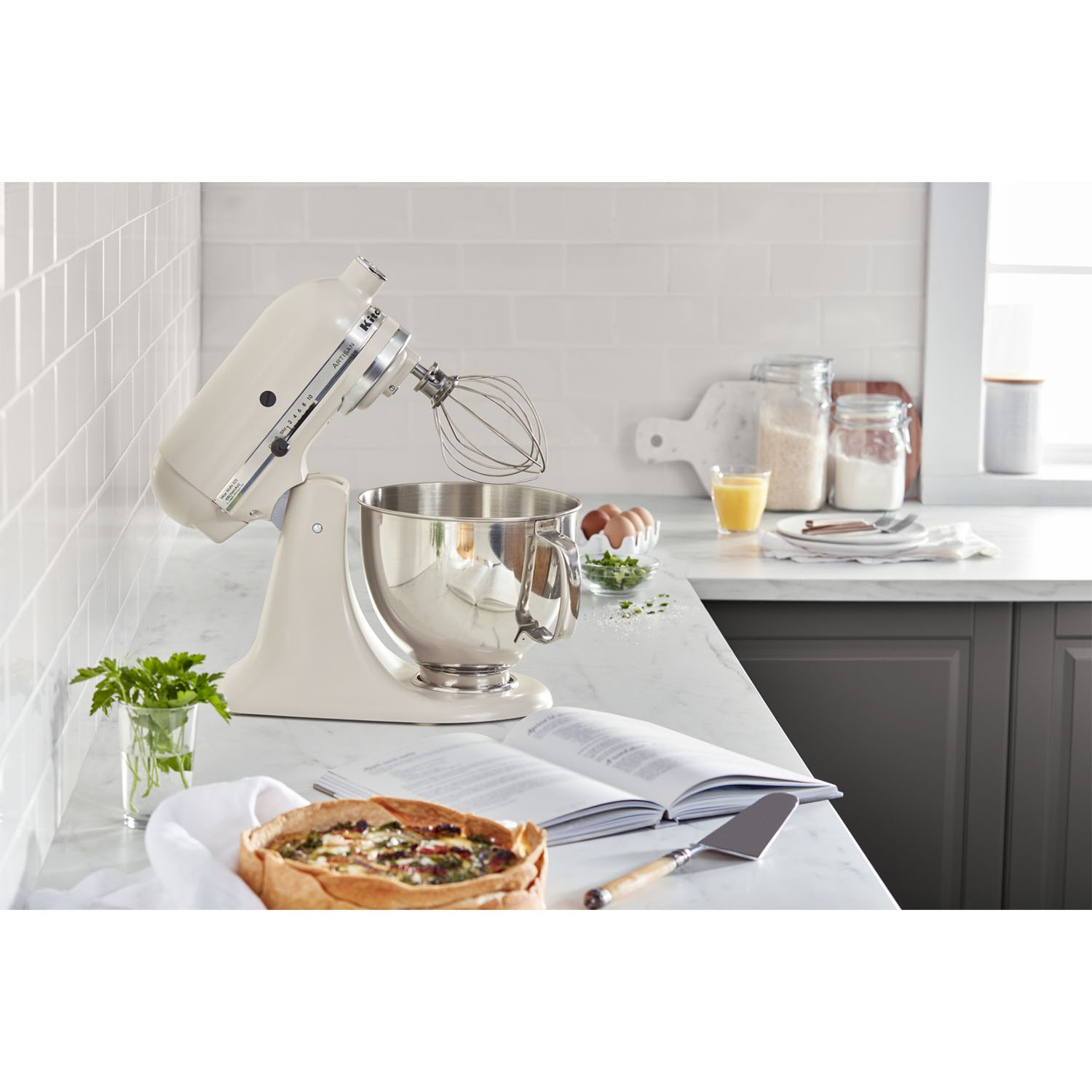 Frullatore KitchenAid color crema che mescola l'impasto. Una quiche e ingredienti sul bancone.